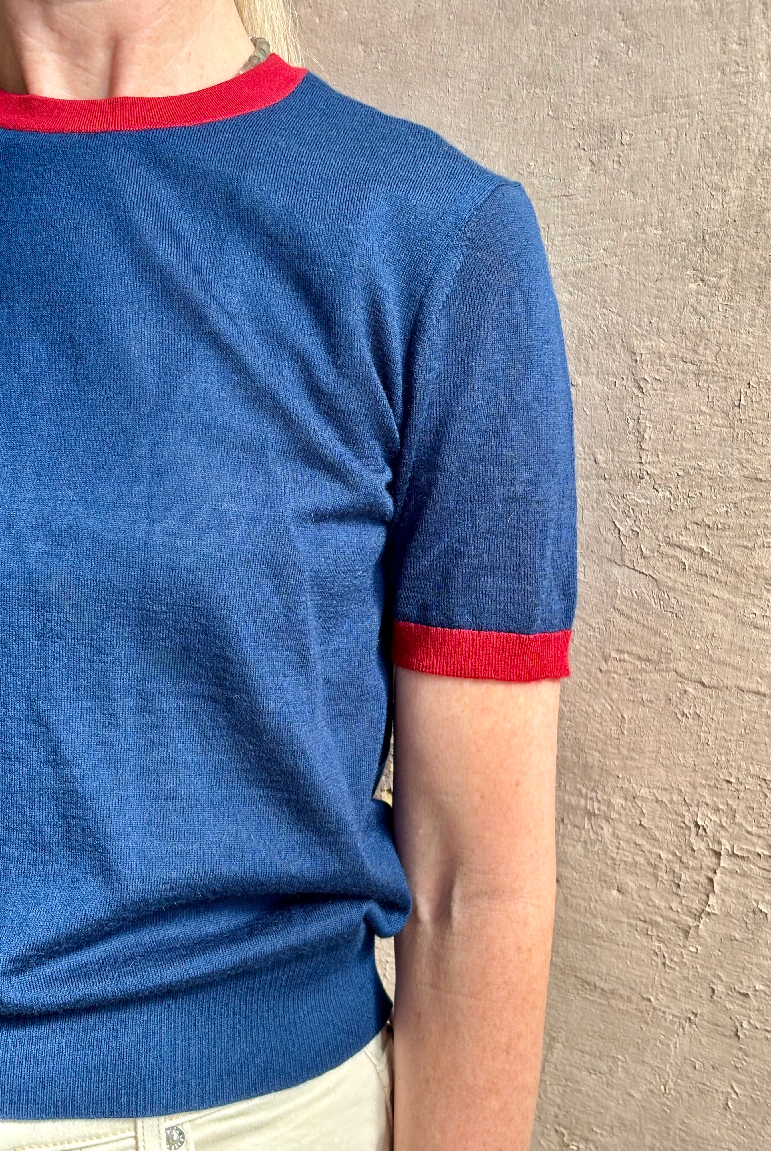 Mature woman wearing women's designer cashmere Airy short sleeve Ringer Tee from Guest in Residence rendered in a navy body with carmine ringer detailing and crafted from 100% lightweight cashmere with a crew neckline