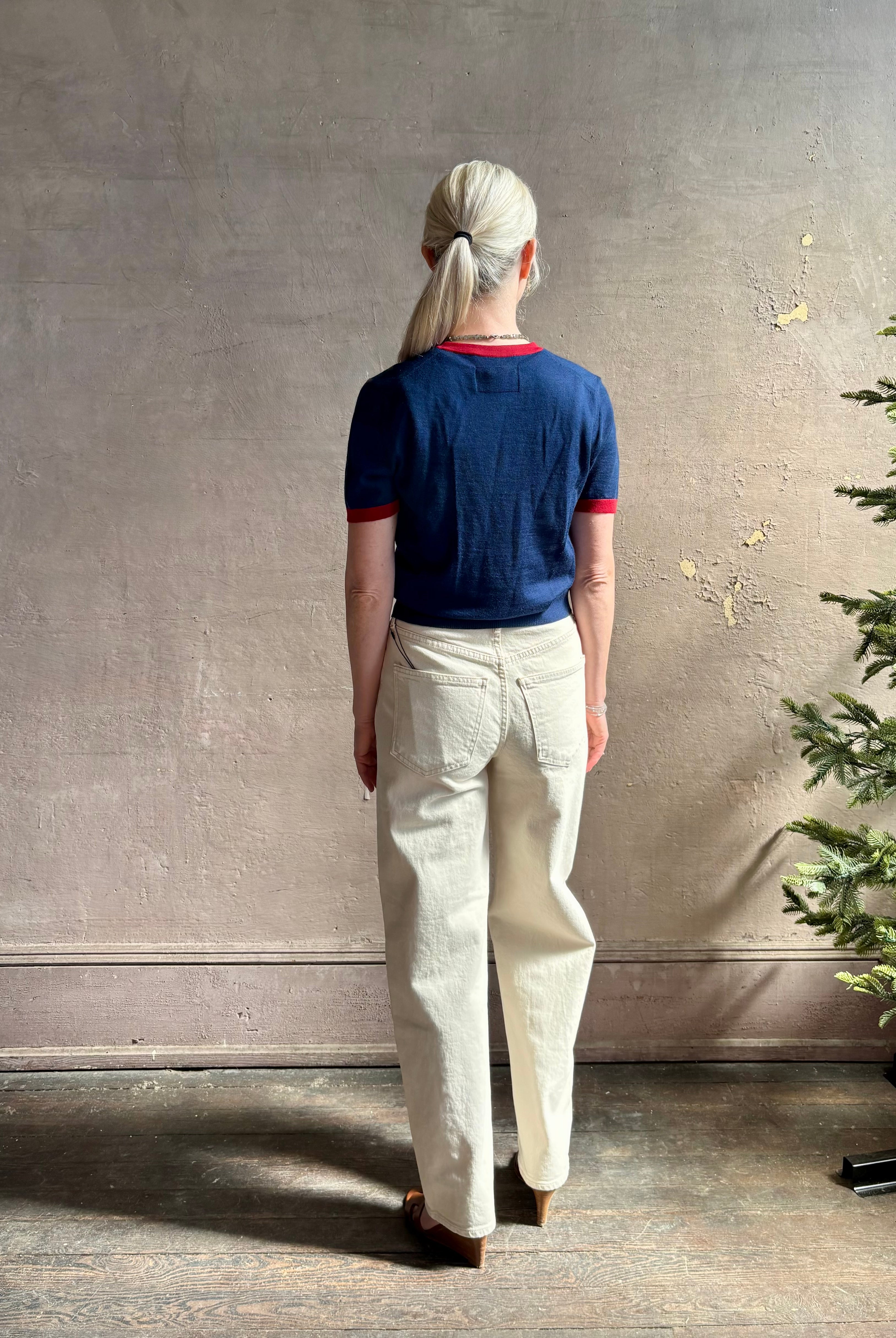 Mature woman wearing women's designer cashmere Airy short sleeve Ringer Tee from Guest in Residence rendered in a navy body with carmine ringer detailing and crafted from 100% lightweight cashmere with a crew neckline