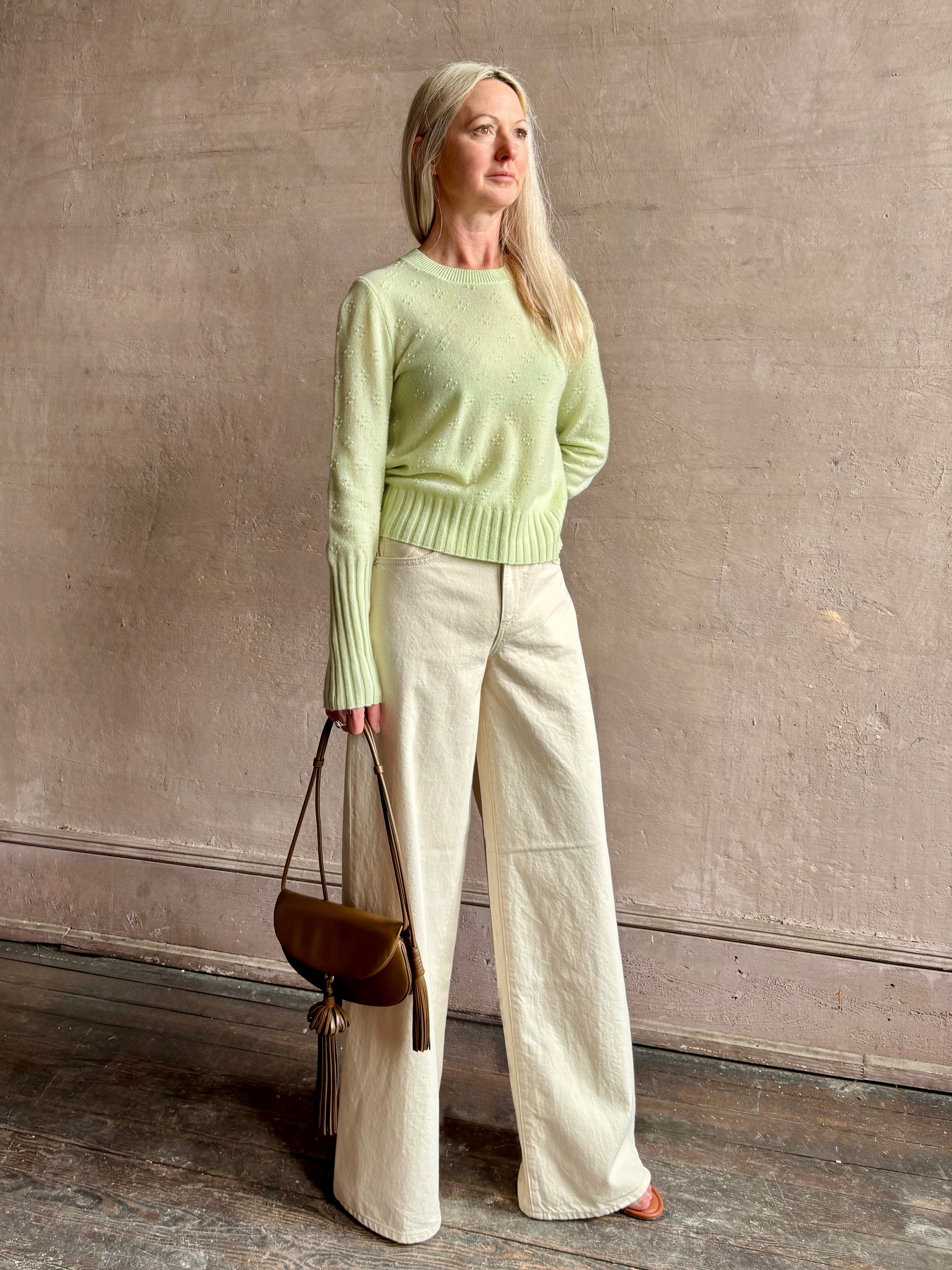 Image of woman wearing luxury cashmere crew neck sweater GUEST IN RESIDENCE Compass Shrunken Crew in Limewash Knitwear with long sleeves and dot detail throughout