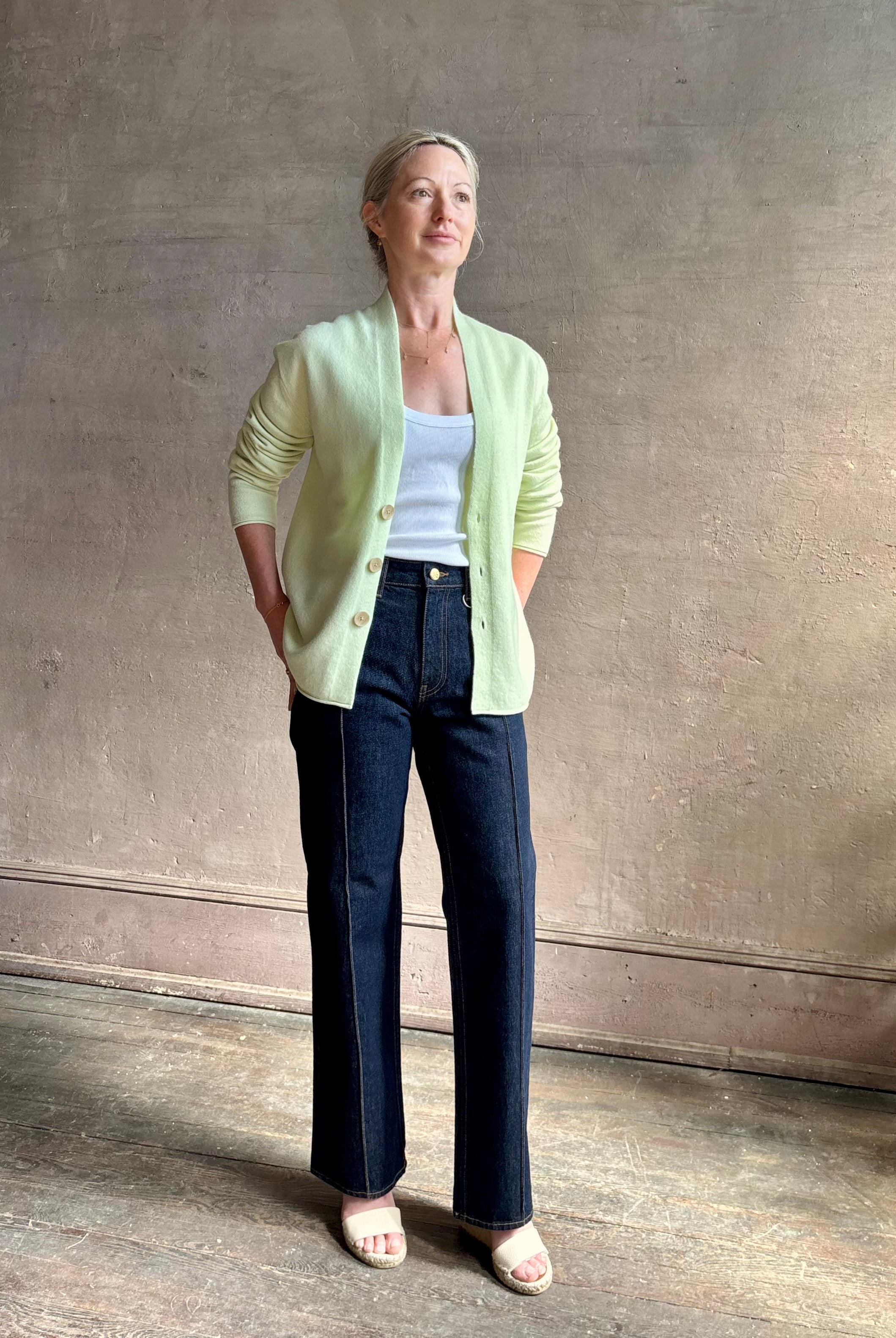 Image of mature woman wearing luxury cashmere sweater GUEST IN RESIDENCE Everywhere Cardigan in Limewash green with long sleeves and three button front v-neck