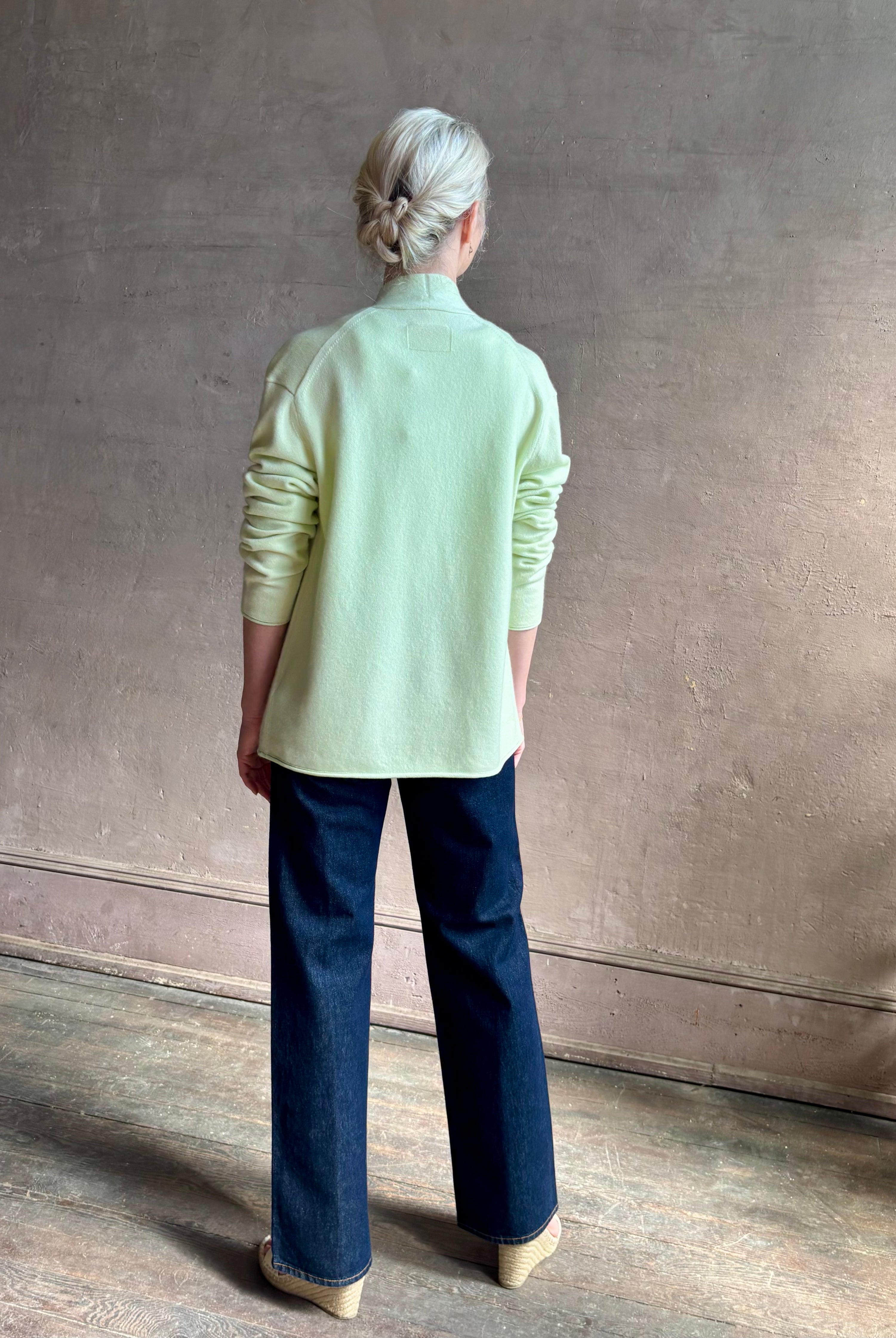 Image of mature woman wearing luxury cashmere sweater GUEST IN RESIDENCE Everywhere Cardigan in Limewash green with long sleeves and three button front v-neck