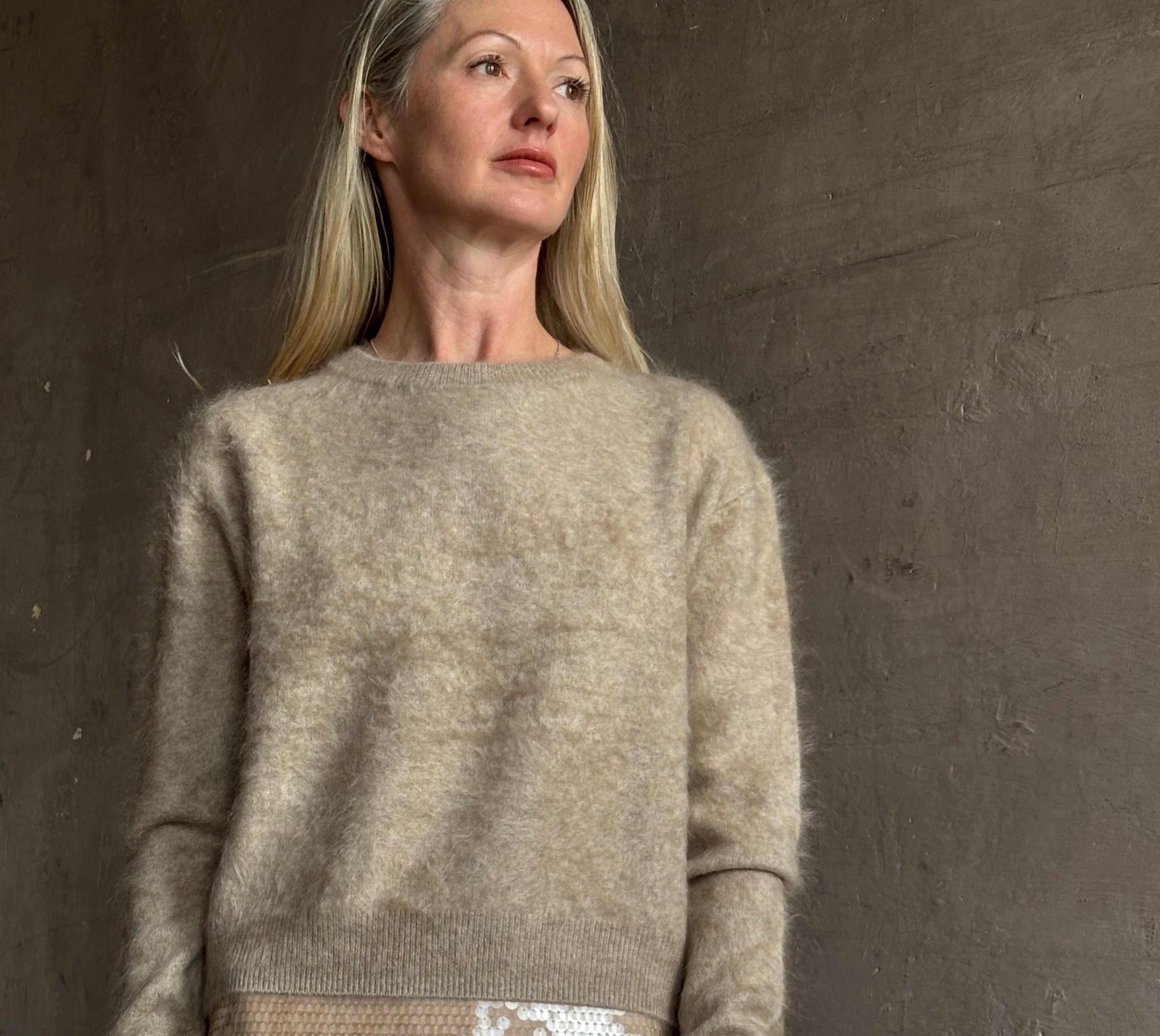 Image of mature model wearing New York luxury women's clothing brand Guest In Residence long-sleeve crew neck brushed cashmere beige sweater