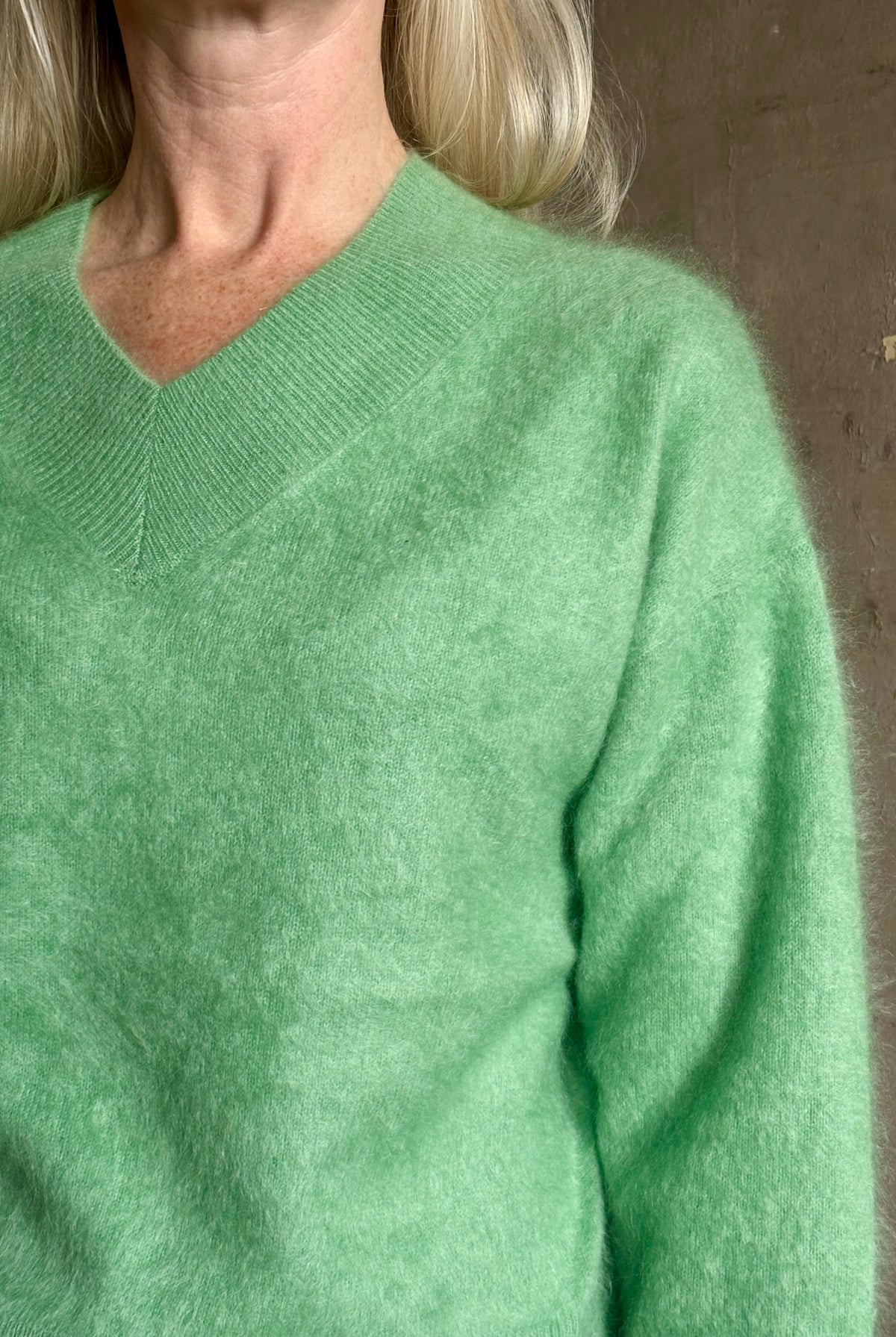 Mature woman wearing Guest in Residence Grizzly Double V Sweater Highland Green brushed cashmere with symmetrical front-and-back V-necklines