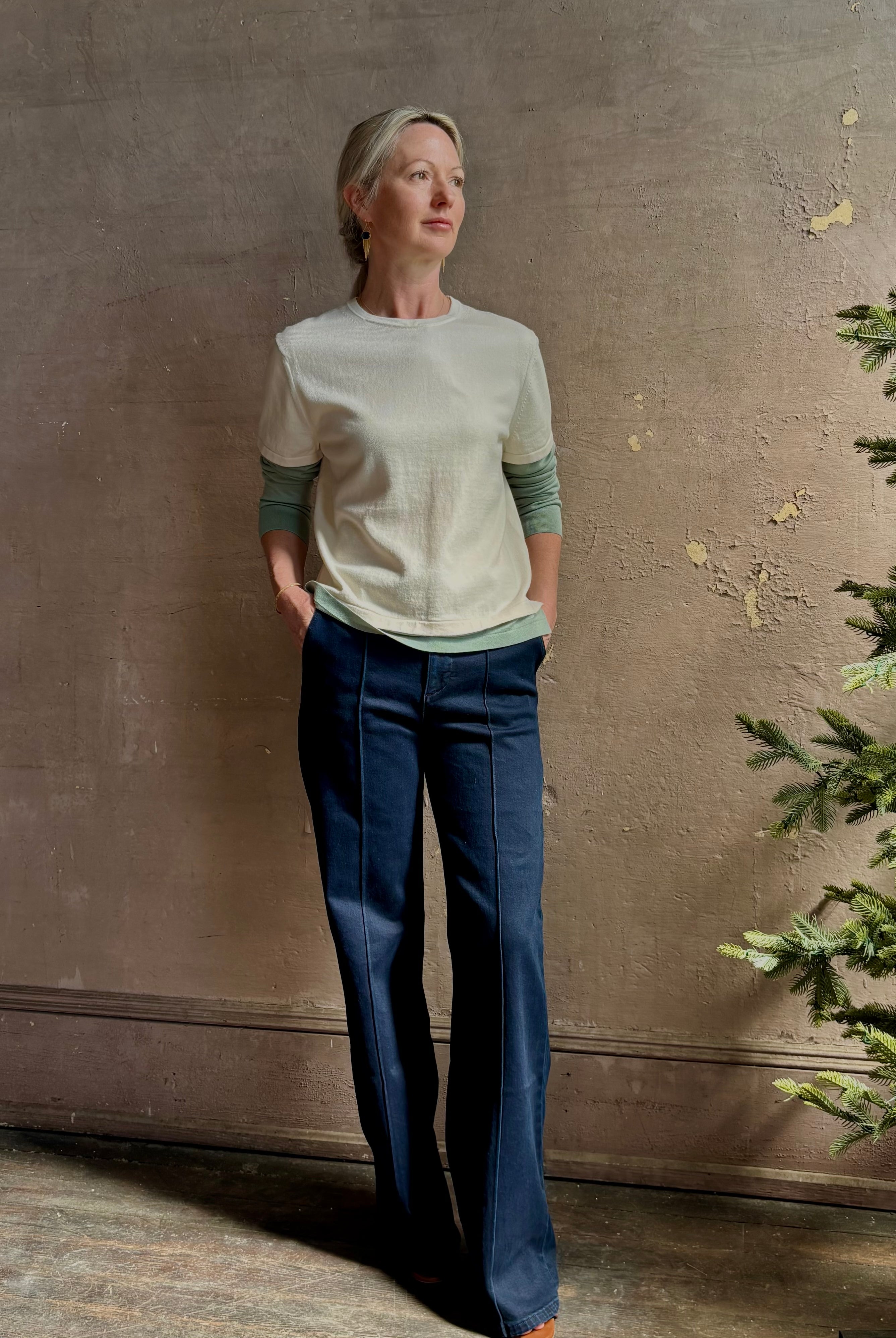 Mature woman wearing elevated luxury Layer Tee Shirt from Guest in Residence rendered in a soft sage brush green and cream colorway and crafted from an exceptional blend of cotton, cashmere, and silk with long sleeves and a crew neckline