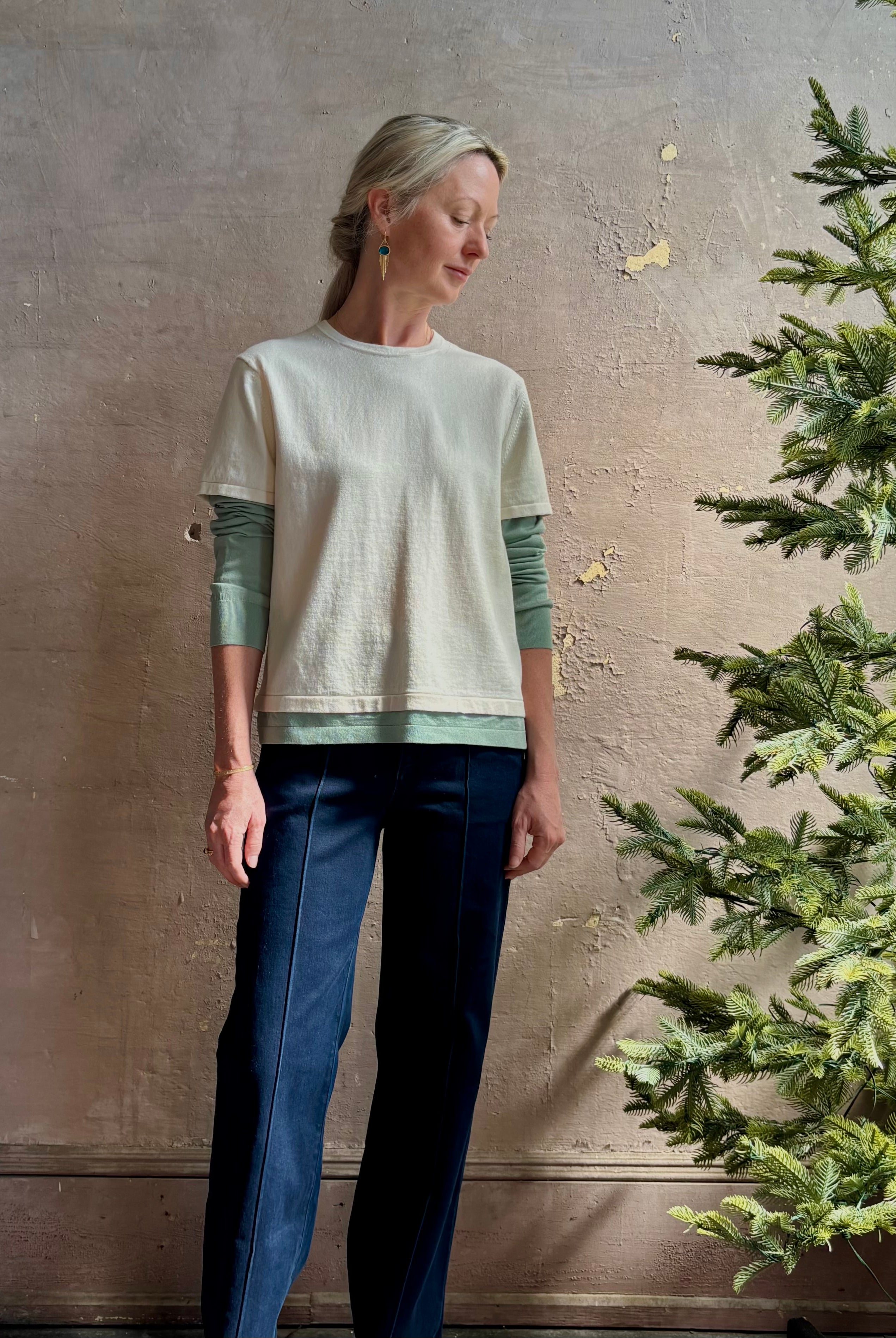 Mature woman wearing elevated luxury Layer Tee Shirt from Guest in Residence rendered in a soft sage brush green and cream colorway and crafted from an exceptional blend of cotton, cashmere, and silk with long sleeves and a crew neckline
