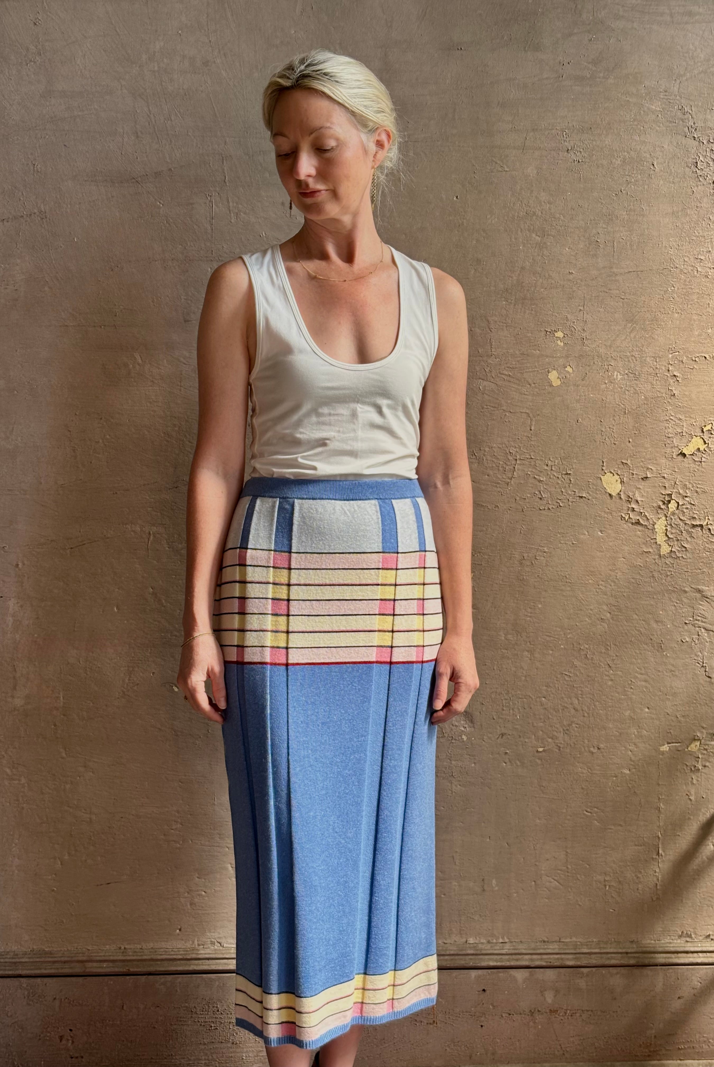 Mature woman wearing Plaited Rib knit pencil Skirt from Guest in Residence rendered in delft blue and crafted from a luxurious blend of silk, linen, nylon, and elastane with wide rib texture down front and back with pink and yellow horizontal stripes at hips and bottom edge