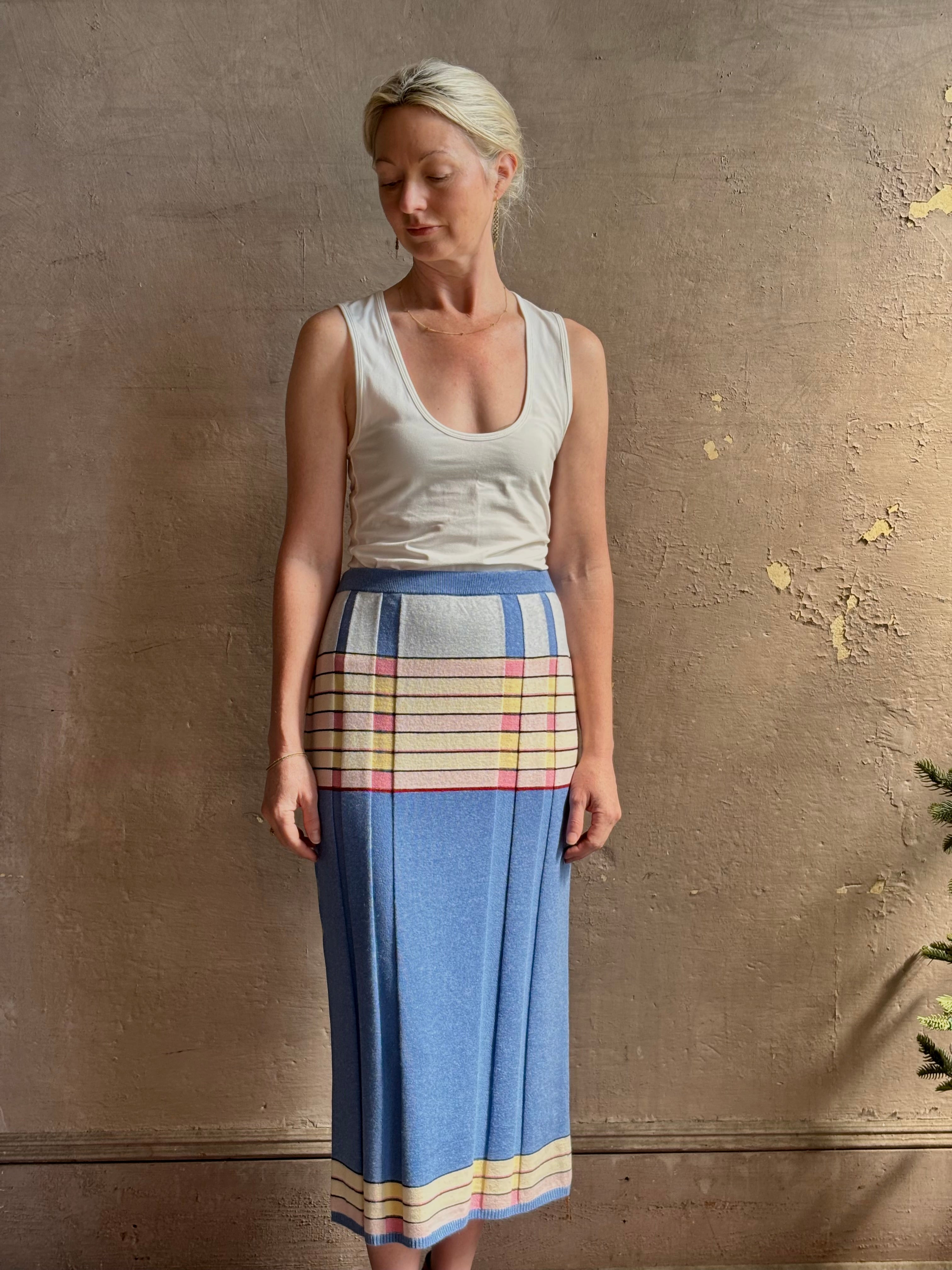 Mature woman wearing Plaited Rib knit pencil Skirt from Guest in Residence rendered in delft blue and crafted from a luxurious blend of silk, linen, nylon, and elastane with wide rib texture down front and back with pink and yellow horizontal stripes at hips and bottom edge