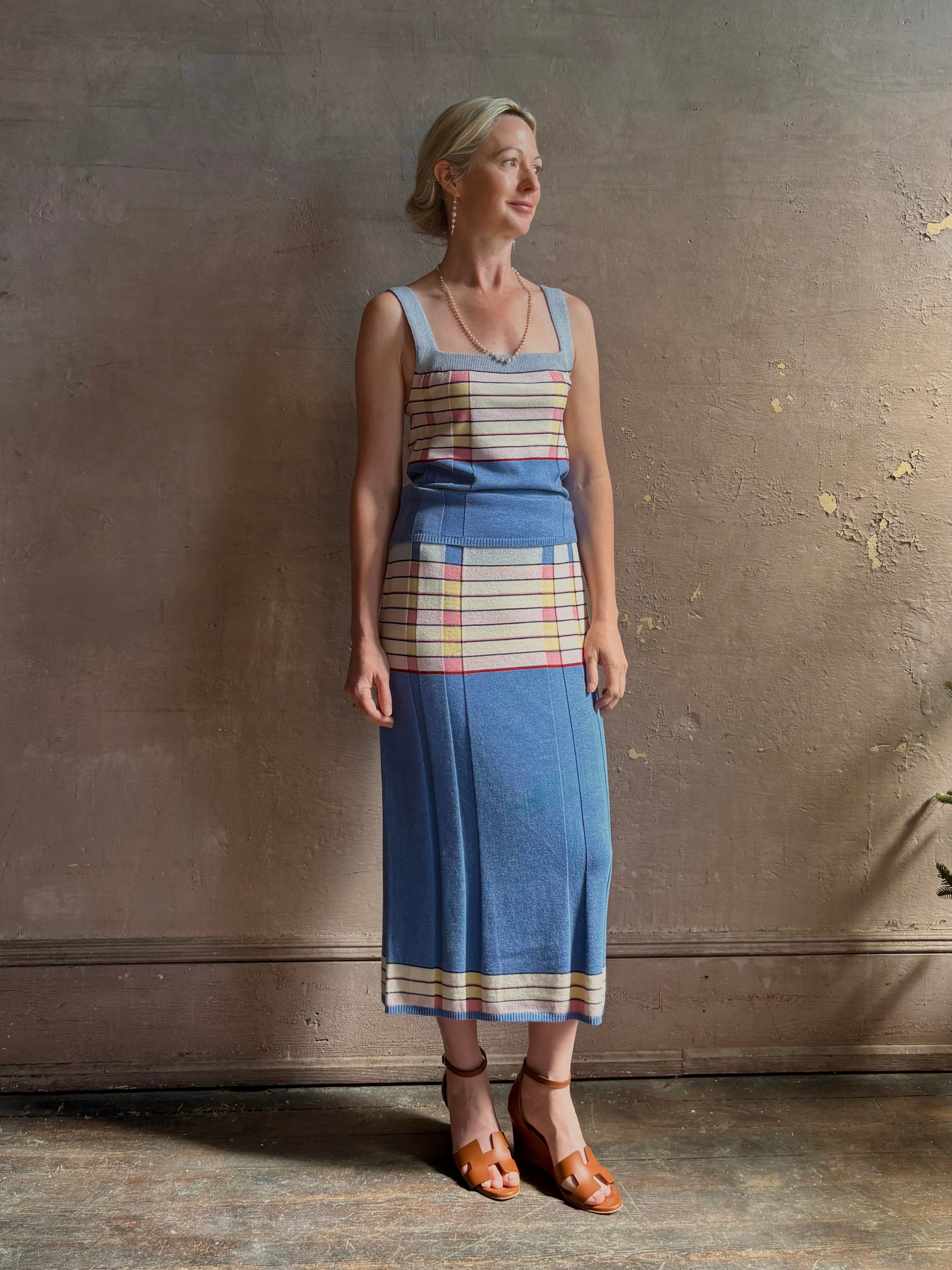 Mature woman wearing Plaited Rib knit pencil Skirt from Guest in Residence rendered in delft blue and crafted from a luxurious blend of silk, linen, nylon, and elastane with wide rib texture down front and back with pink and yellow horizontal stripes at hips and bottom edge