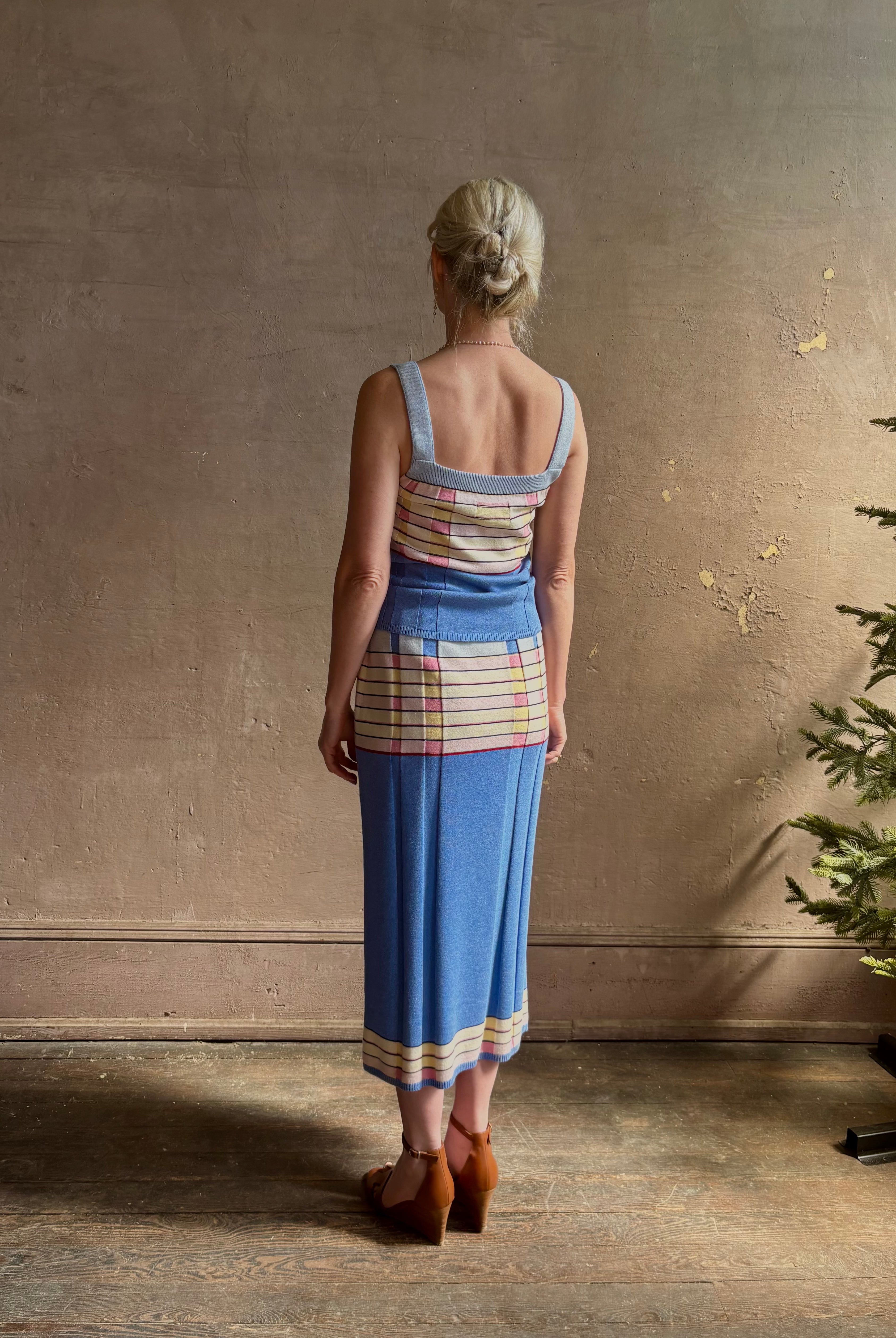 Mature woman wearing Plaited Rib knit pencil Skirt from Guest in Residence rendered in delft blue and crafted from a luxurious blend of silk, linen, nylon, and elastane with wide rib texture down front and back with pink and yellow horizontal stripes at hips and bottom edge