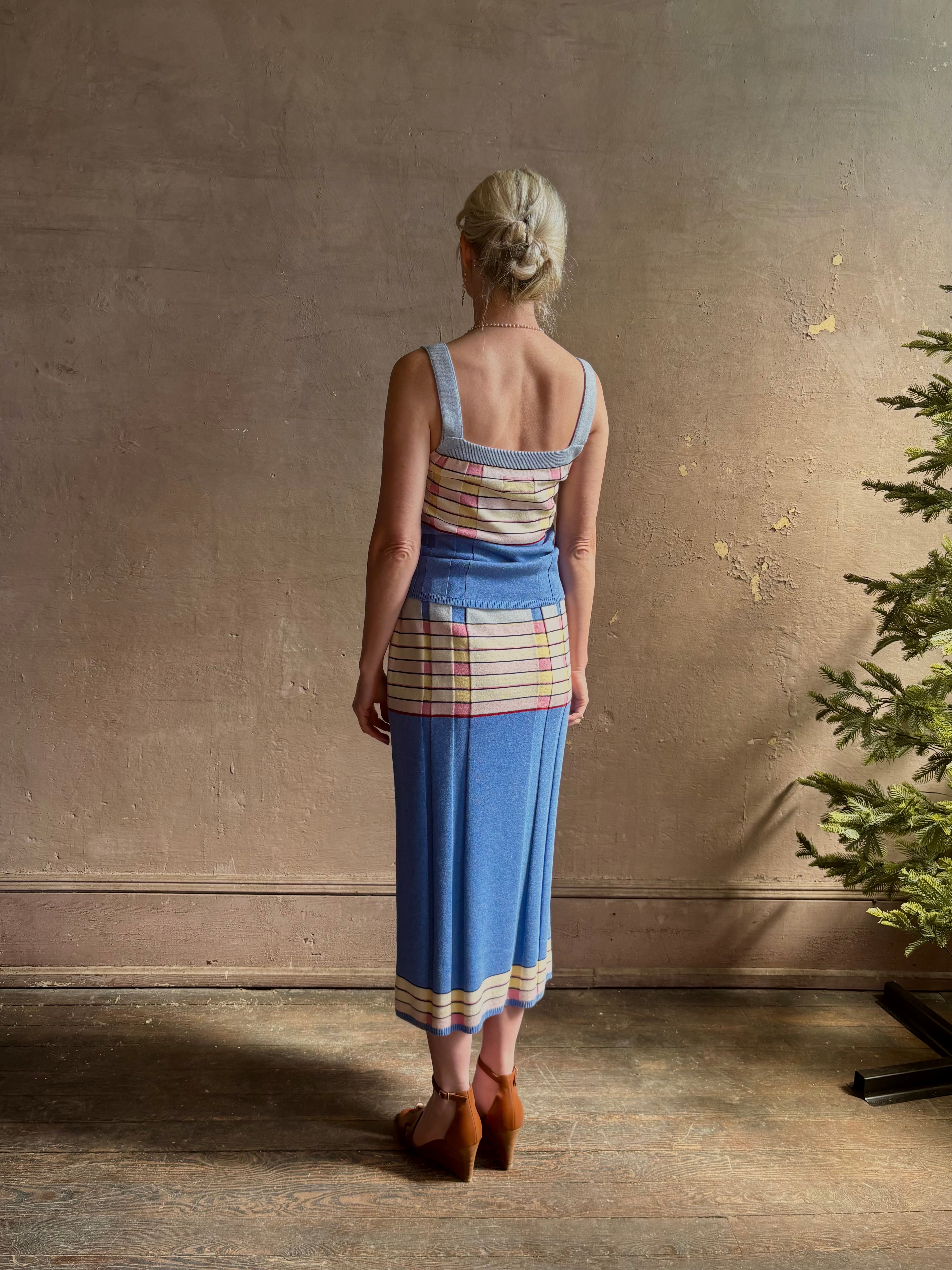 Mature woman wearing Plaited Rib knit pencil Skirt from Guest in Residence rendered in delft blue and crafted from a luxurious blend of silk, linen, nylon, and elastane with wide rib texture down front and back with pink and yellow horizontal stripes at hips and bottom edge