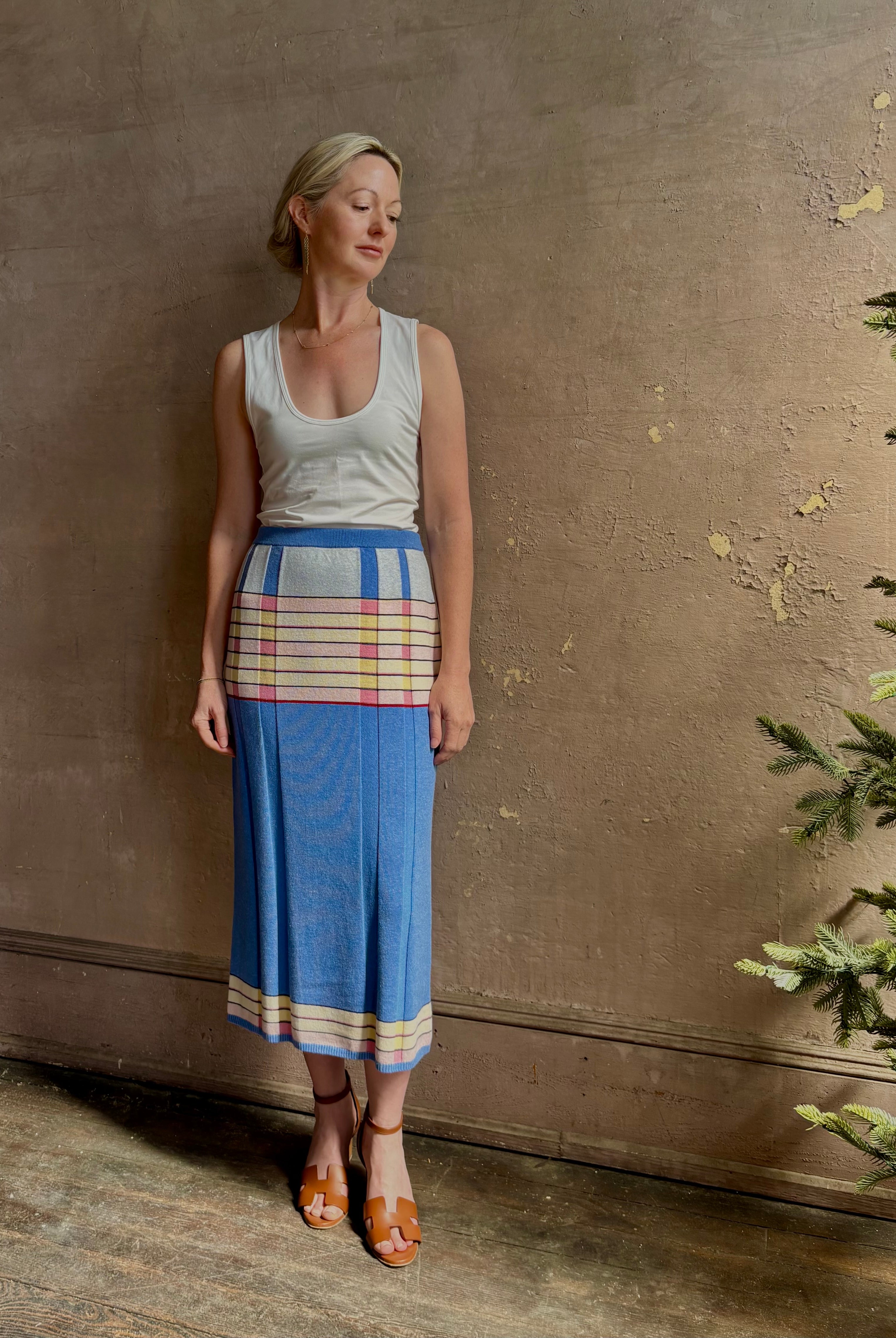 Mature woman wearing Plaited Rib knit pencil Skirt from Guest in Residence rendered in delft blue and crafted from a luxurious blend of silk, linen, nylon, and elastane with wide rib texture down front and back with pink and yellow horizontal stripes at hips and bottom edge