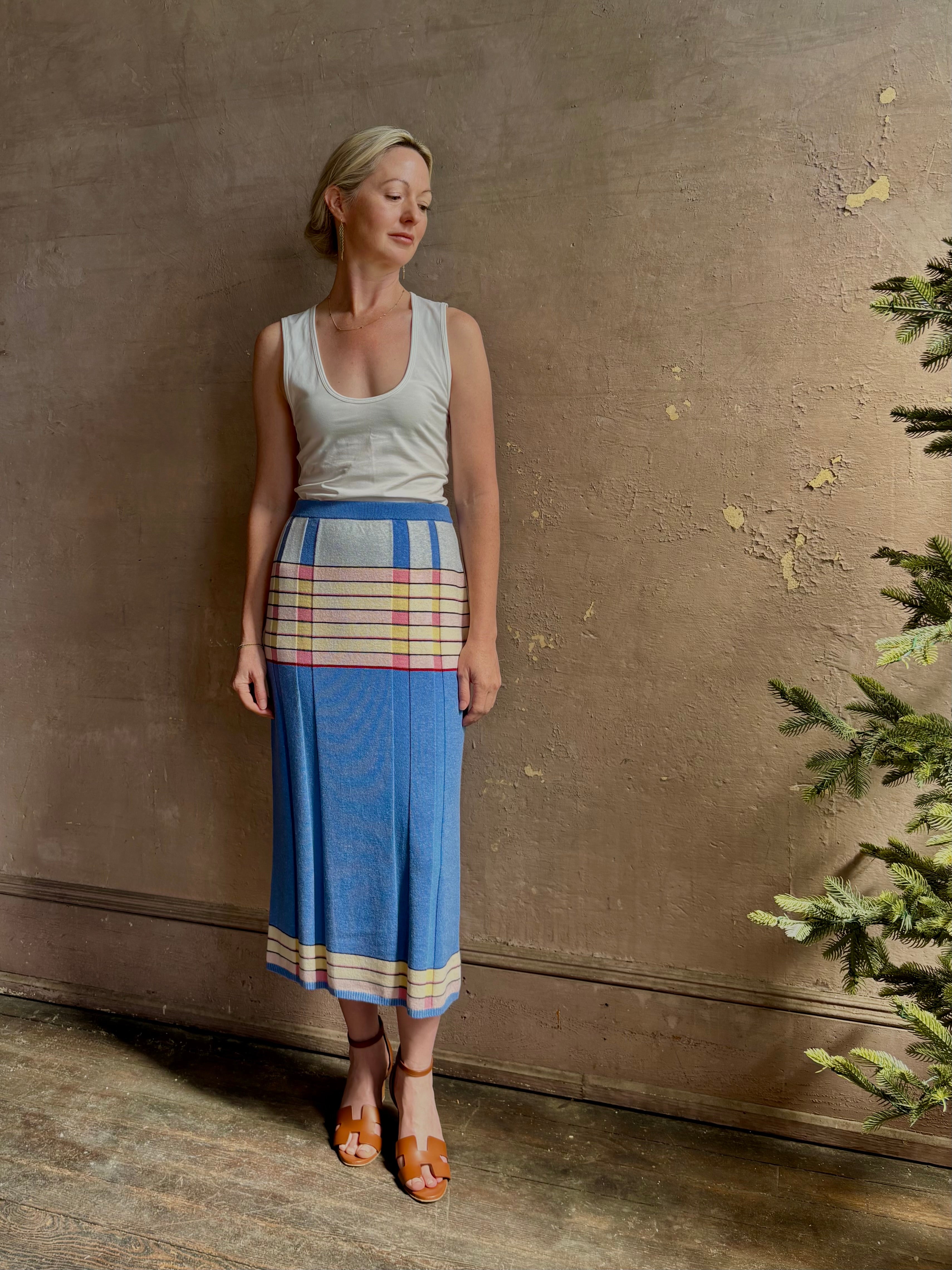 Mature woman wearing Plaited Rib knit pencil Skirt from Guest in Residence rendered in delft blue and crafted from a luxurious blend of silk, linen, nylon, and elastane with wide rib texture down front and back with pink and yellow horizontal stripes at hips and bottom edge