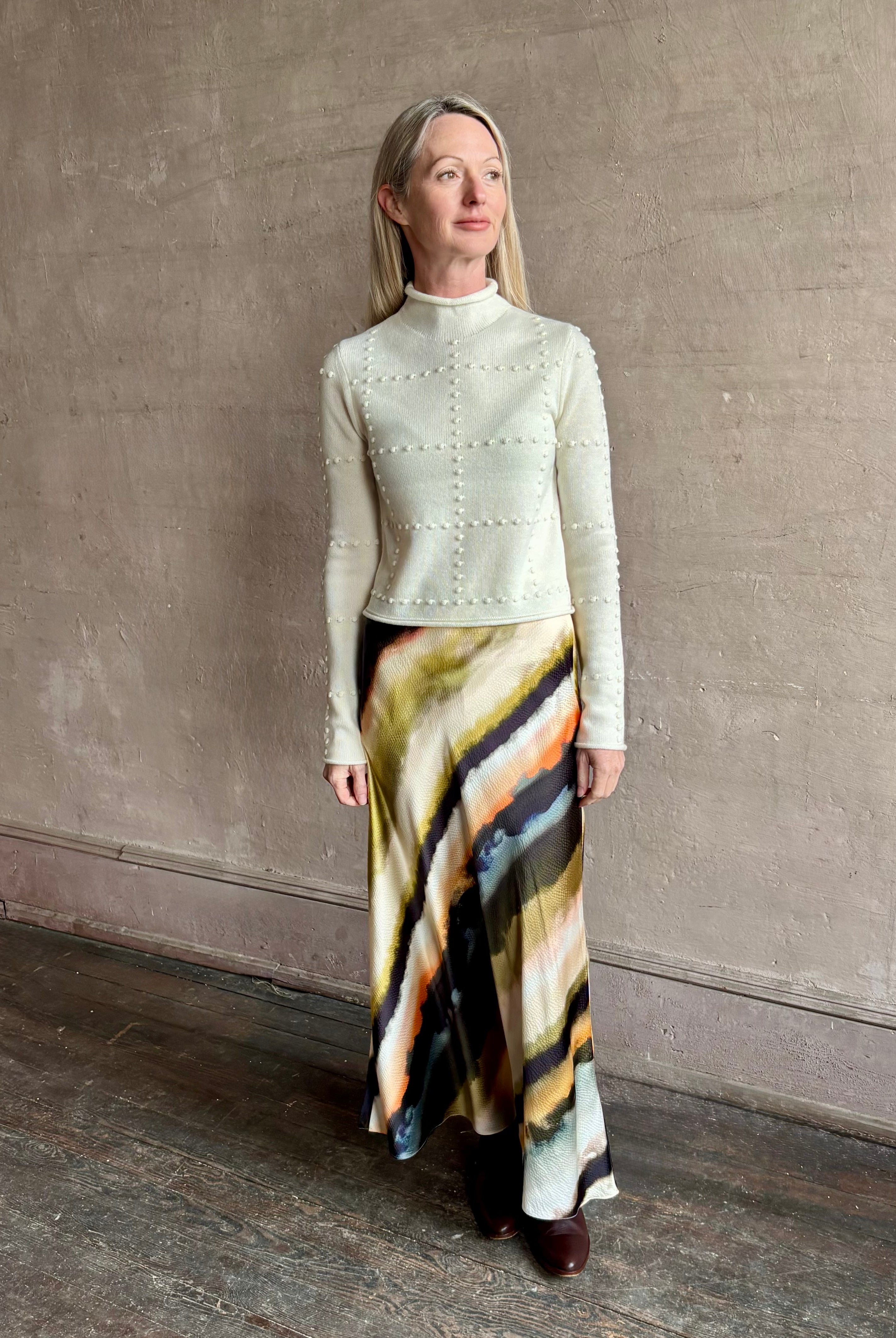 Image of mature woman wearing a cream cashmere blend sweater from NYC based celebrity brand Guest in Residence with geometric texture pattern