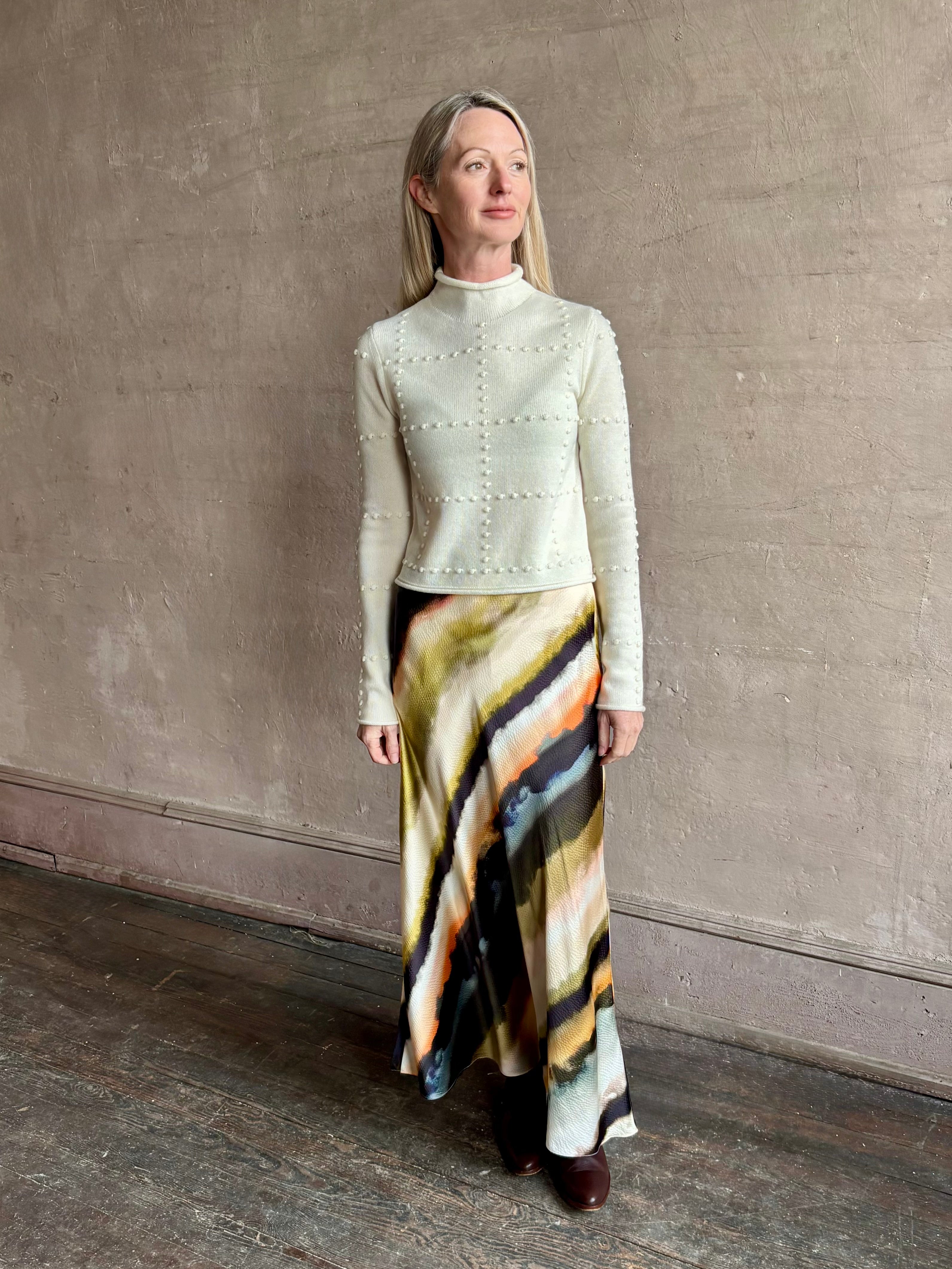 Image of mature woman wearing a cream cashmere blend sweater from NYC based celebrity brand Guest in Residence with geometric texture pattern