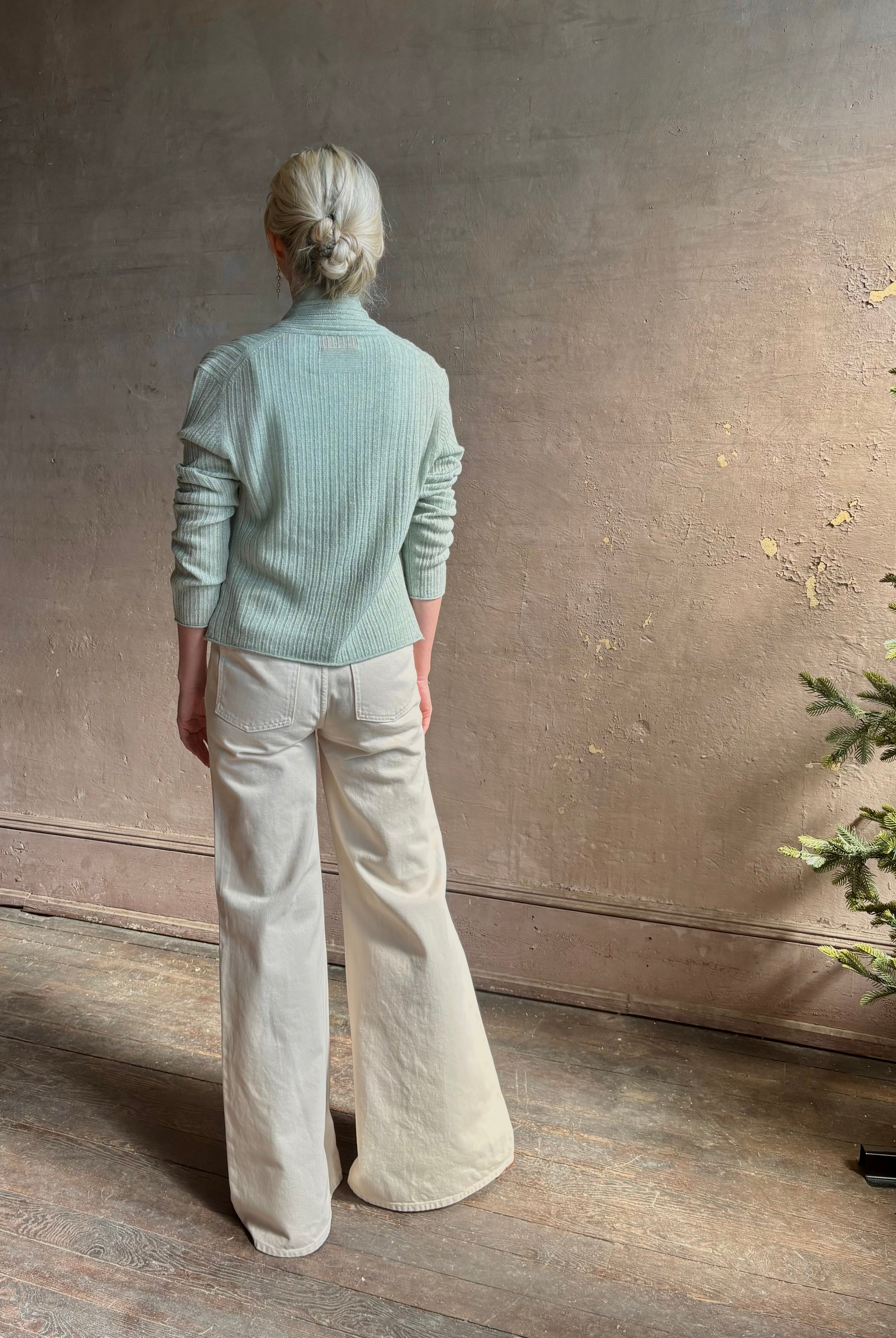 Mature woman wearing Rib Stealth Cardigan from Guest in Residence rendered in a serene sage brush aqua green and crafted from a refined blend of 58% cashmere and 42% linen with long sleeves and a hidden hook and eye closure