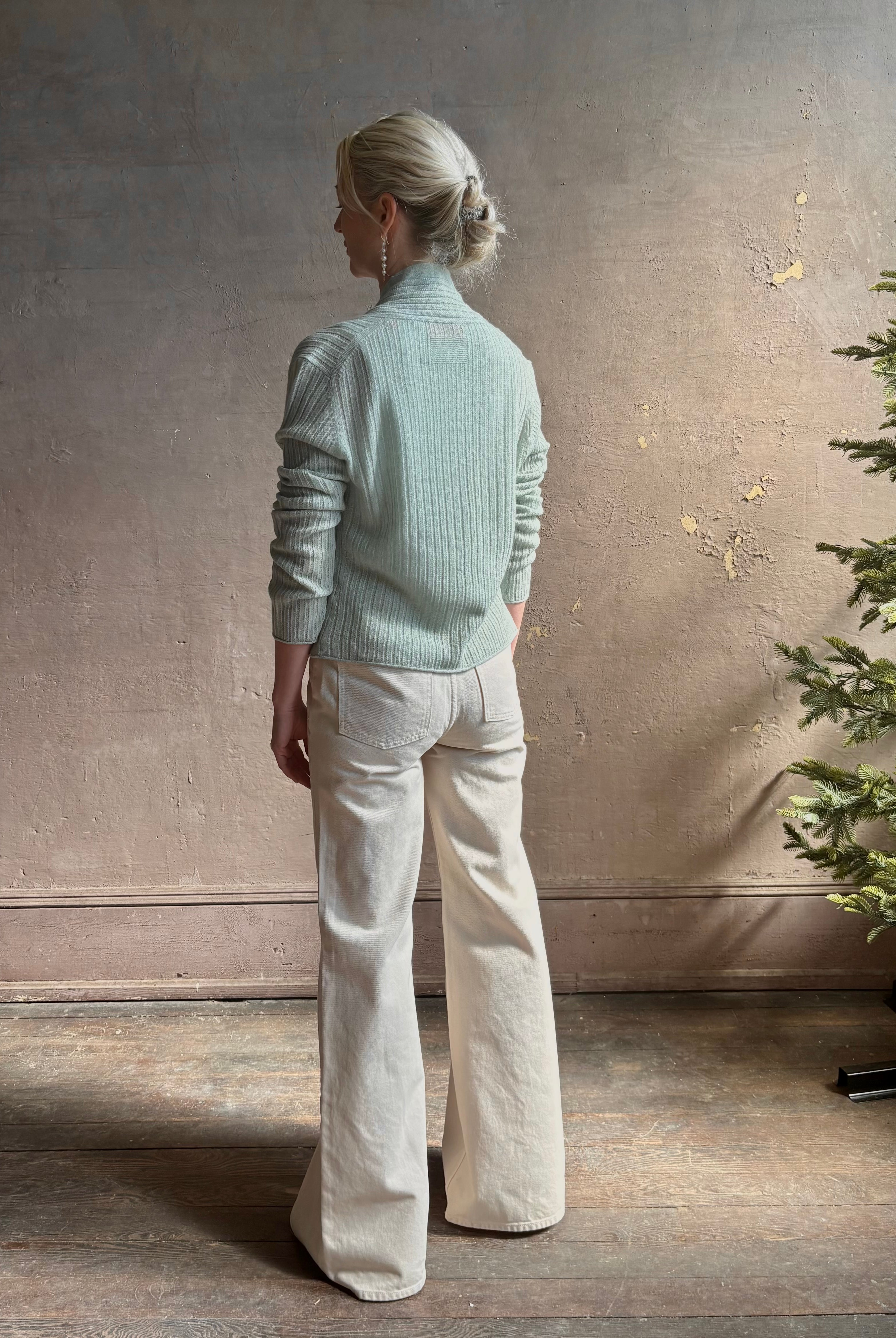 Mature woman wearing Rib Stealth Cardigan from Guest in Residence rendered in a serene sage brush aqua green and crafted from a refined blend of 58% cashmere and 42% linen with long sleeves and a hidden hook and eye closure