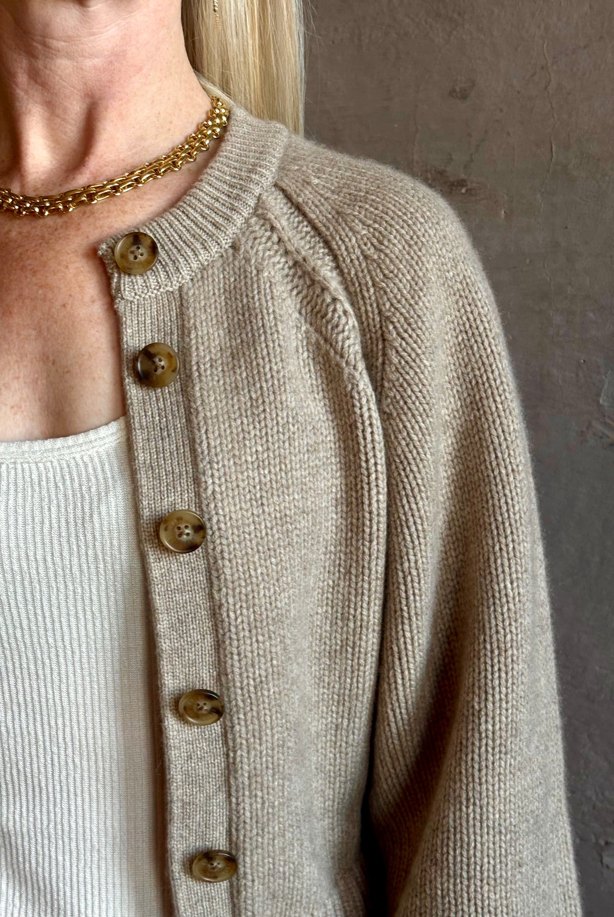 Mature woman wearing Guest in Residence Sculpted Cardigan in Taupe medium gauge cashmere raglan sleeves button front fitted waist softly structured