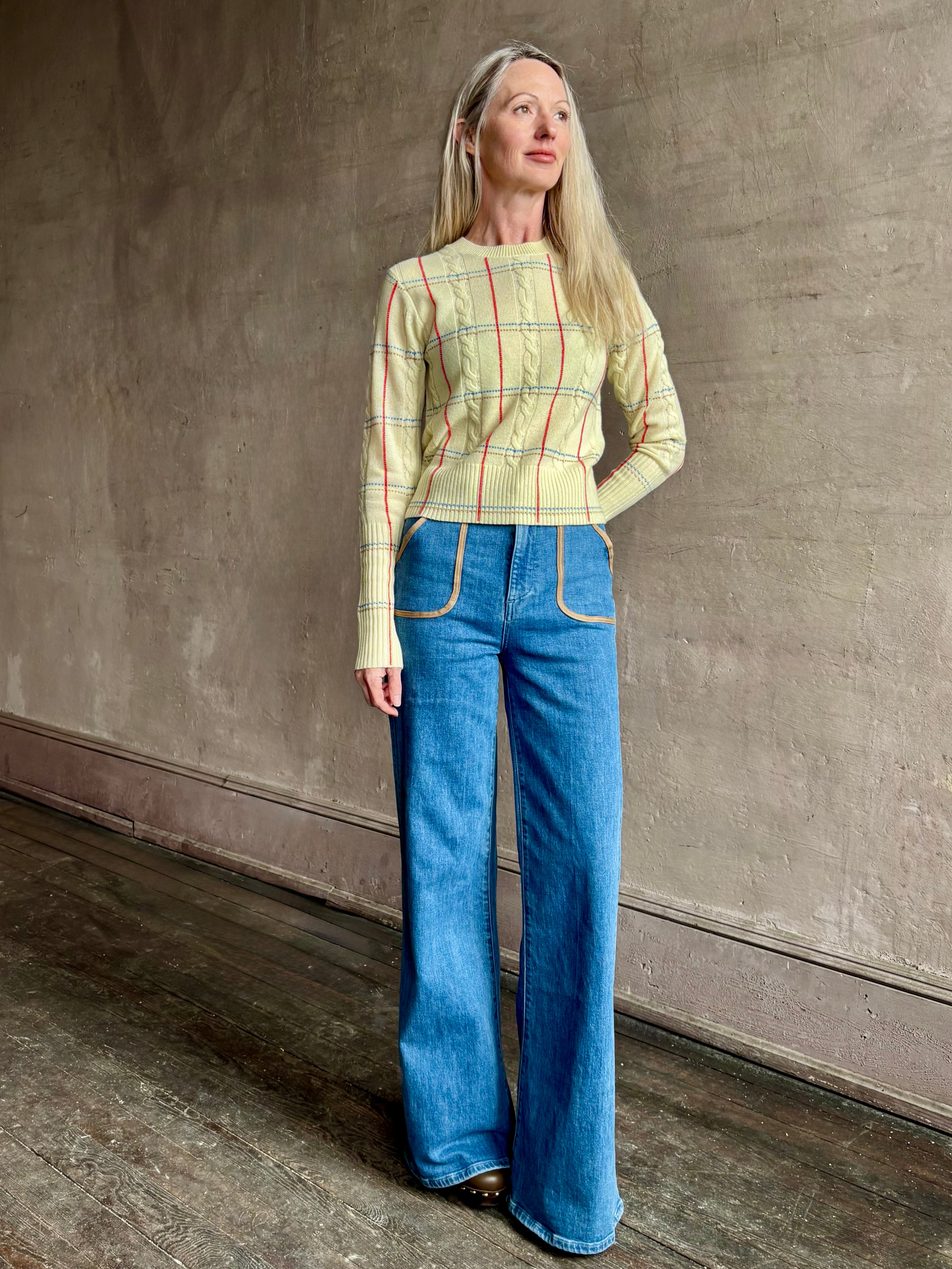 Image of woman wearing designer Guest in Residence yellow combo sweater with cable texture and subtle red, blue and beige plaid stripes pattern