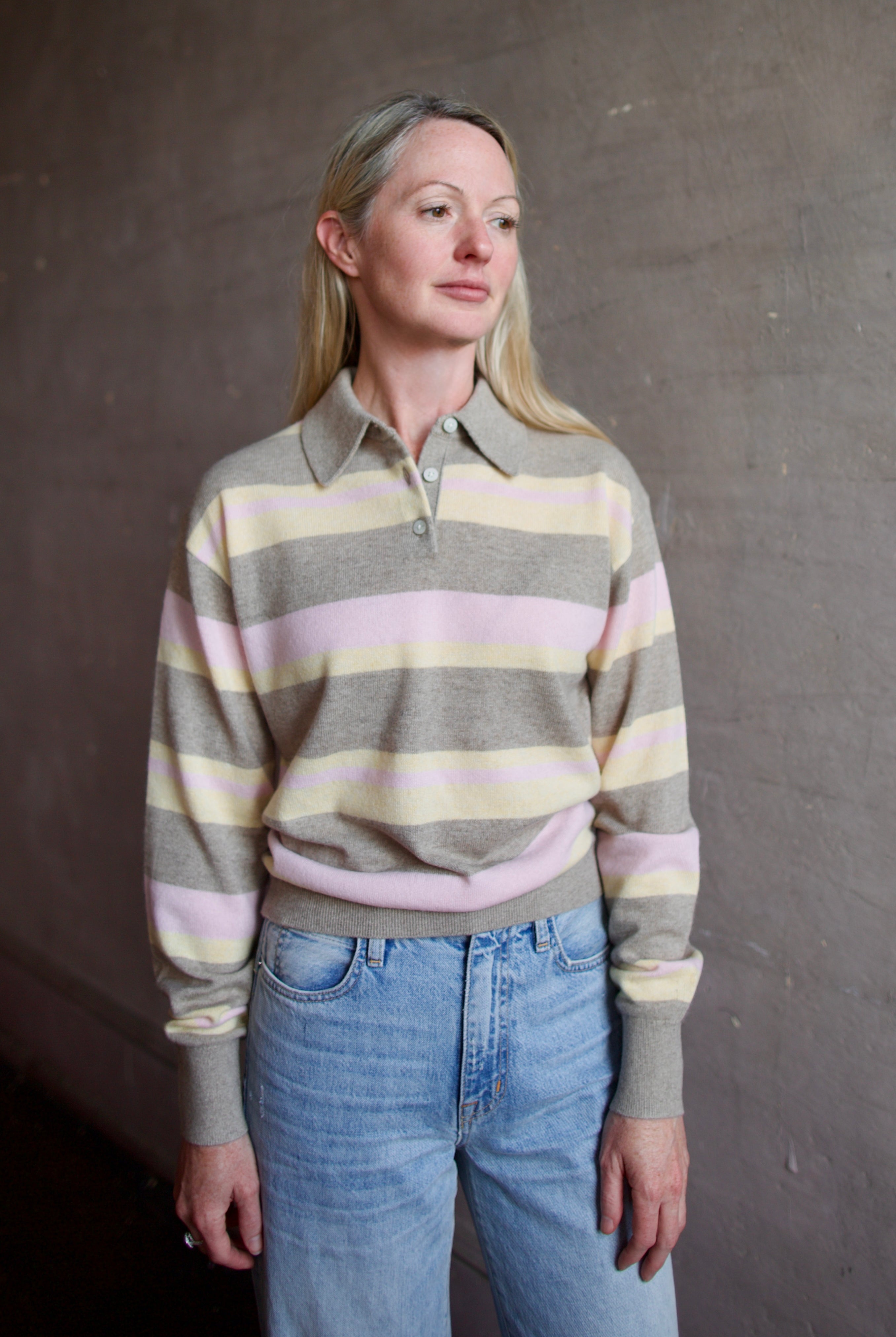 Image of model wearing a Guest in Residence striped cashmere sweater and jeans against a plain background