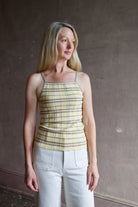 Model wearing premium designer Guest in Residence Plaid Tank top in butter yellow with taupe and white plaid pattern in lightweight silk linen blend