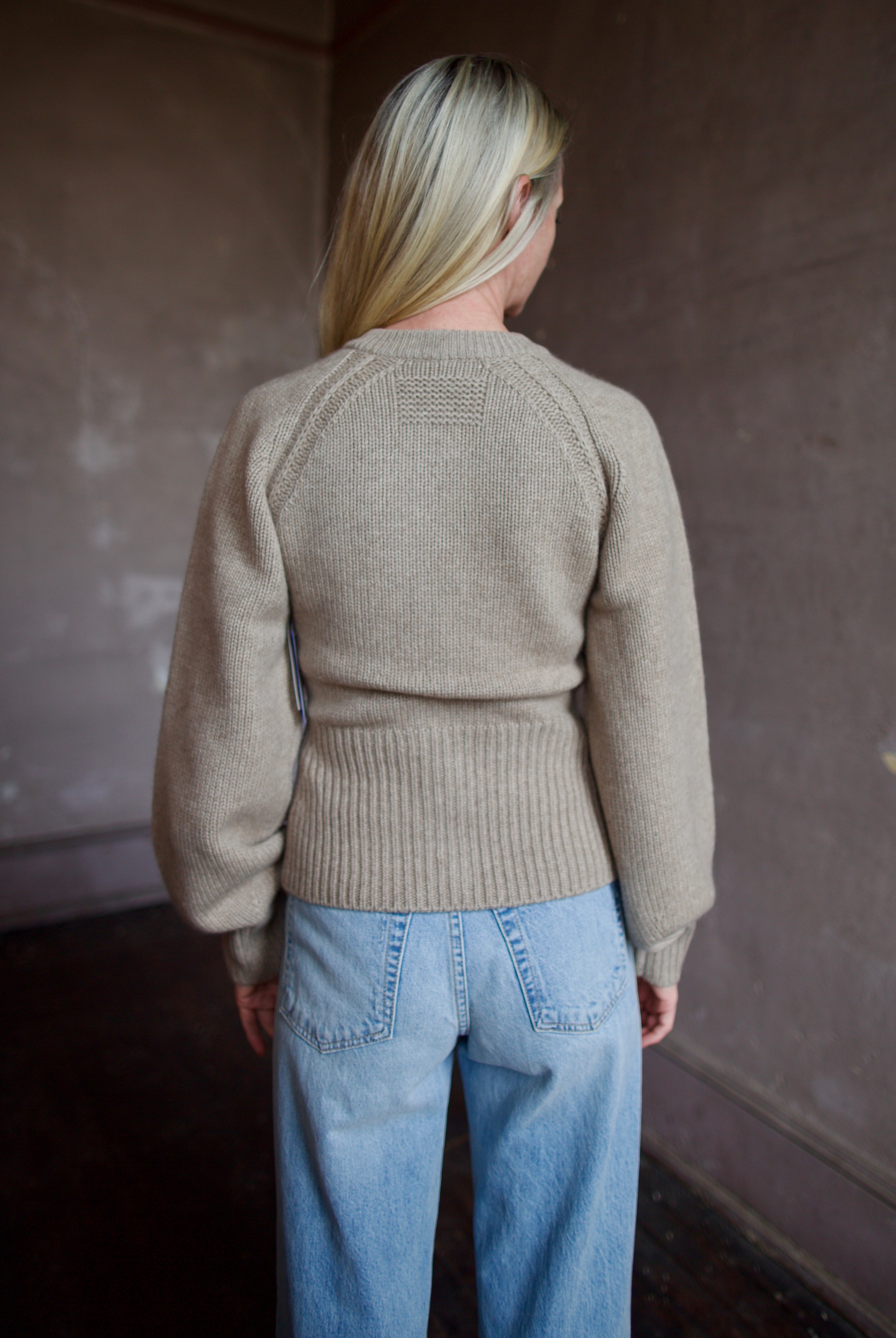 Back of model wearing a beige Guest in Residence cashmere cardigan with Slvrlake denim