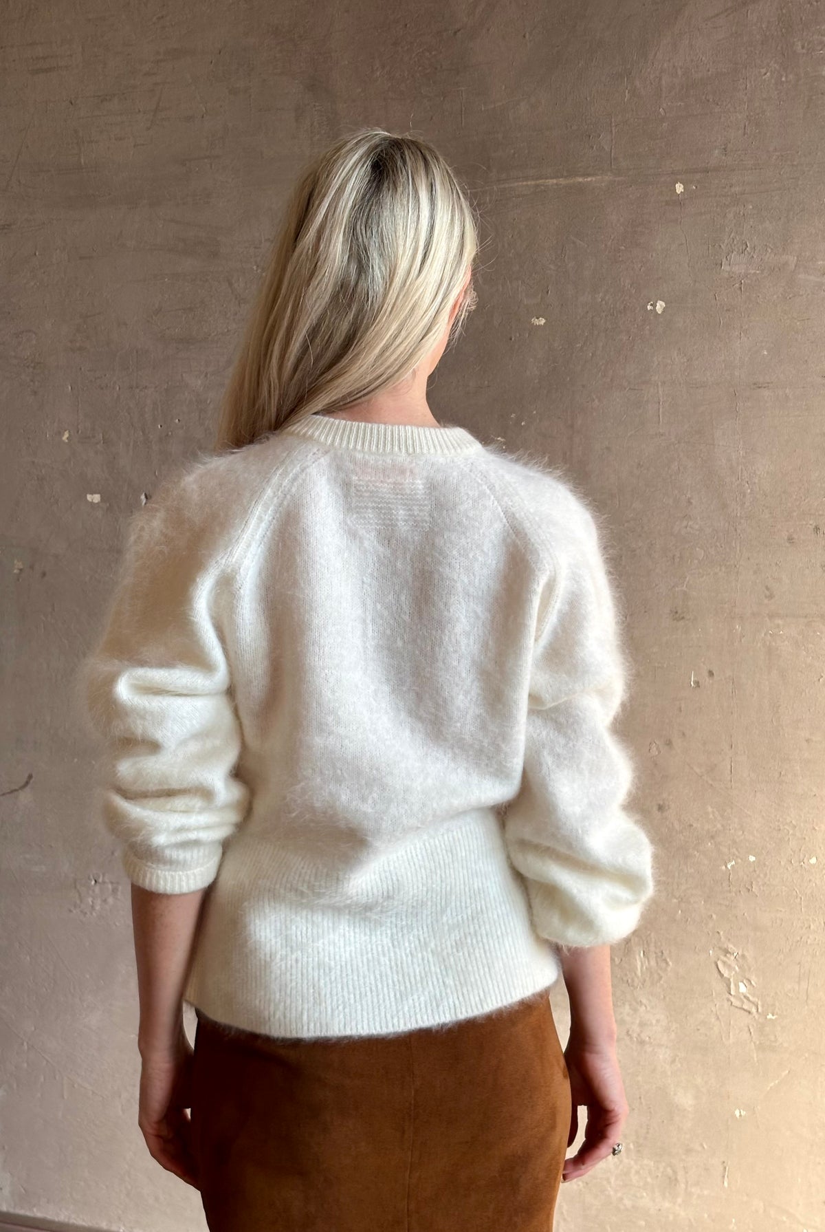 Back image of a Mature woman wearing Guest in Residence’s Grizzly Sculptured Cream brushed cashmere cardigan with crew neck fitted ribbed waistband and henley style long sleeves