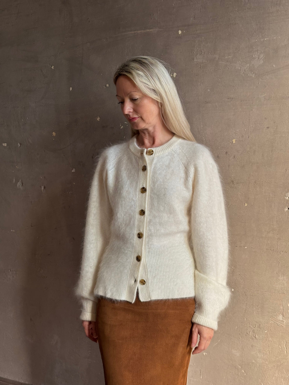 Mature woman wearing Guest in Residence’s Grizzly Sculptured Cream brushed cashmere cardigan ribbed trims brown buttons down front henley style long sleeves