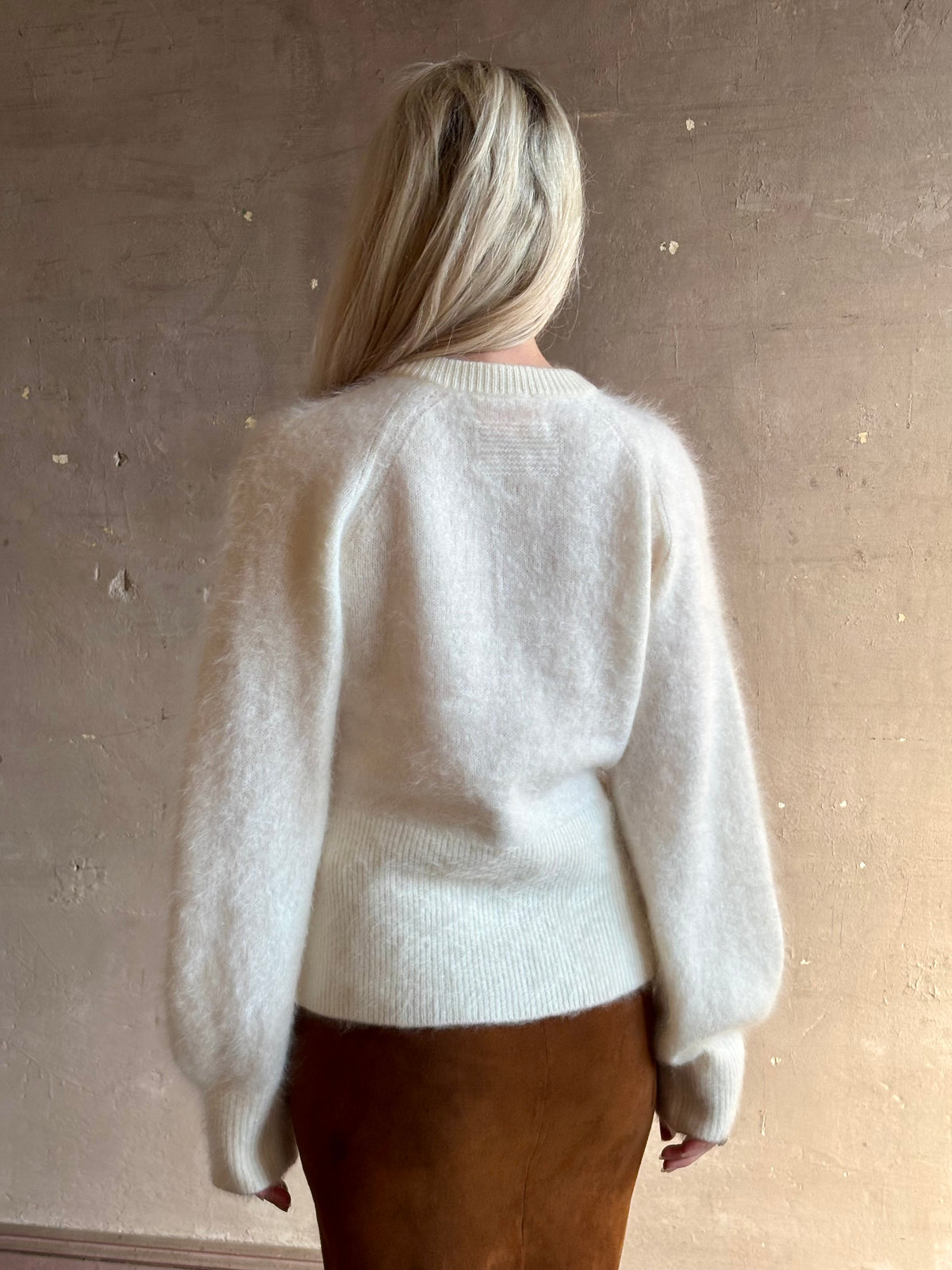 Close up rear image of Guest in Residence Grizzly sculpted cardigan in brushed cashmere with feminine sihlouette and fitted ribbed waistband and henley style long sleeves