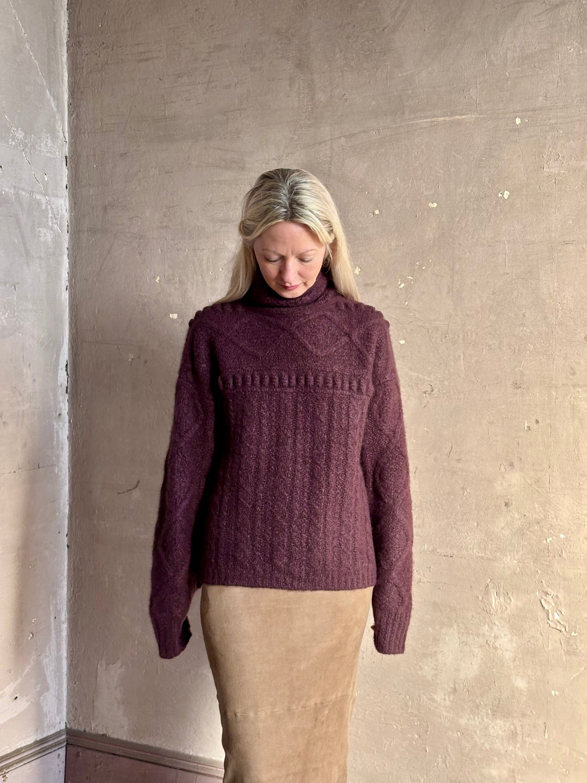 Mature woman wearing a dark plum purple cable-knit turtleneck cashmere silk comfy sweater by Gigi Hadid Guest in Residence
