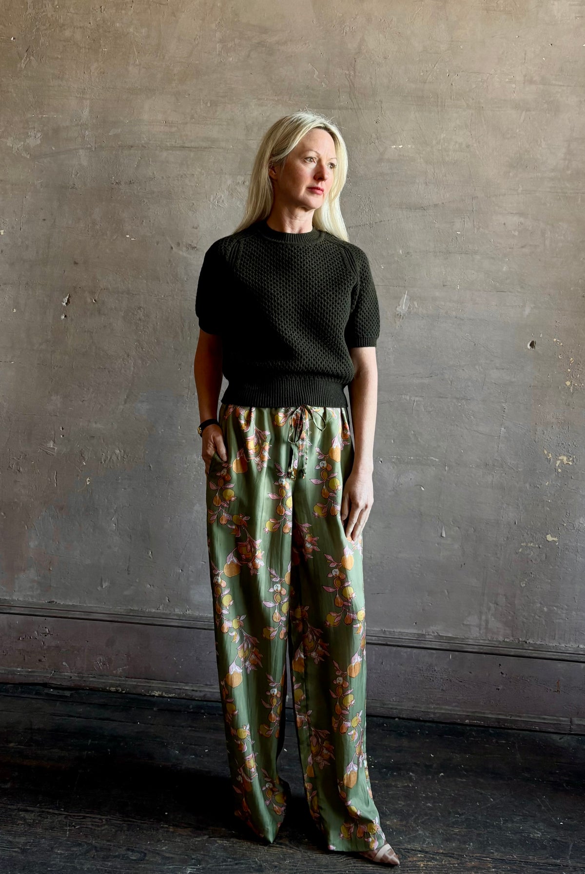 Mature woman wearing Hannah Artwear Azra silk Pant Khaki habotai with vibrant pomegranate print relaxed straight leg Fluid artisan-printed