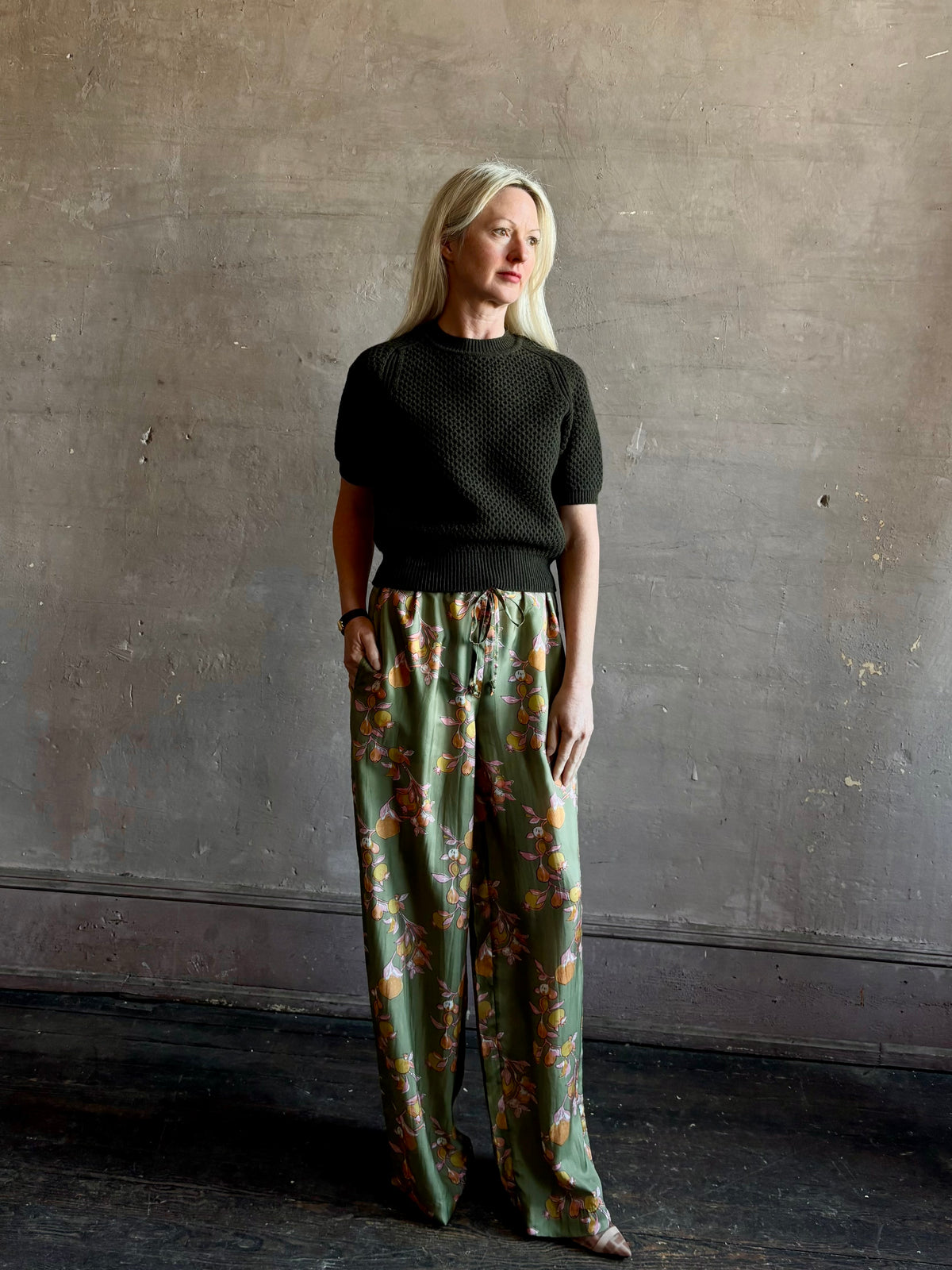 Mature woman wearing Hannah Artwear Azra silk Pant Khaki habotai with vibrant pomegranate print relaxed straight leg Fluid artisan-printed
