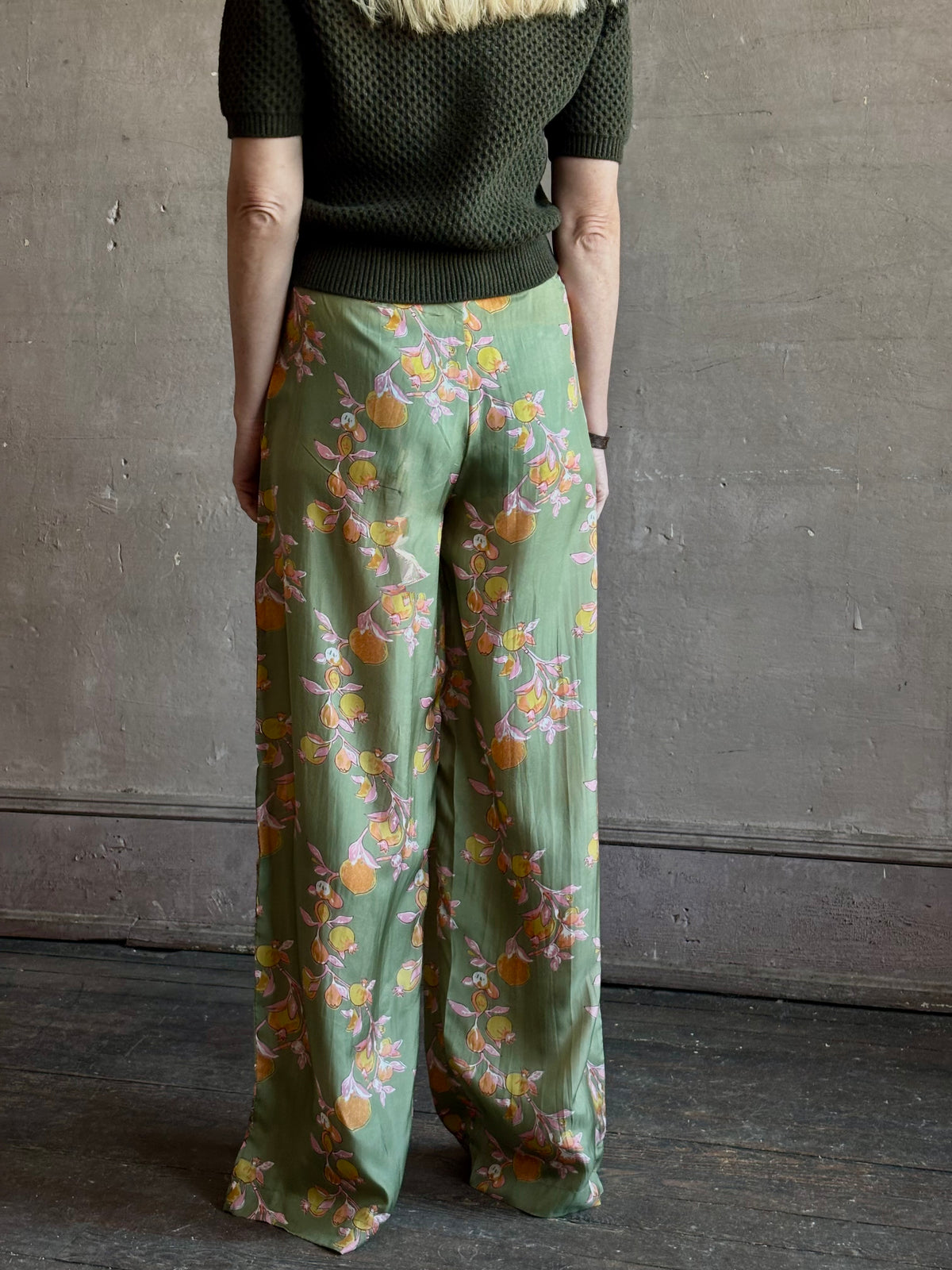 Mature woman wearing Hannah Artwear Azra silk Pant Khaki habotai with vibrant pomegranate print relaxed straight leg Fluid artisan-printed