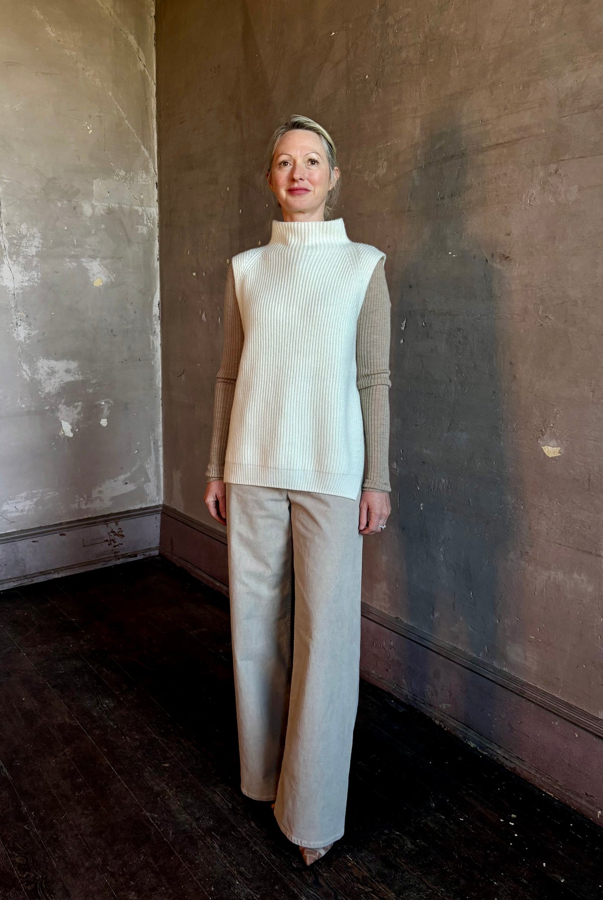 Mature woman wearing Kujten's Erika Funnel Neck Sweater in Off-White cashmere Parisian luxury layering side snap closure intricate modern design