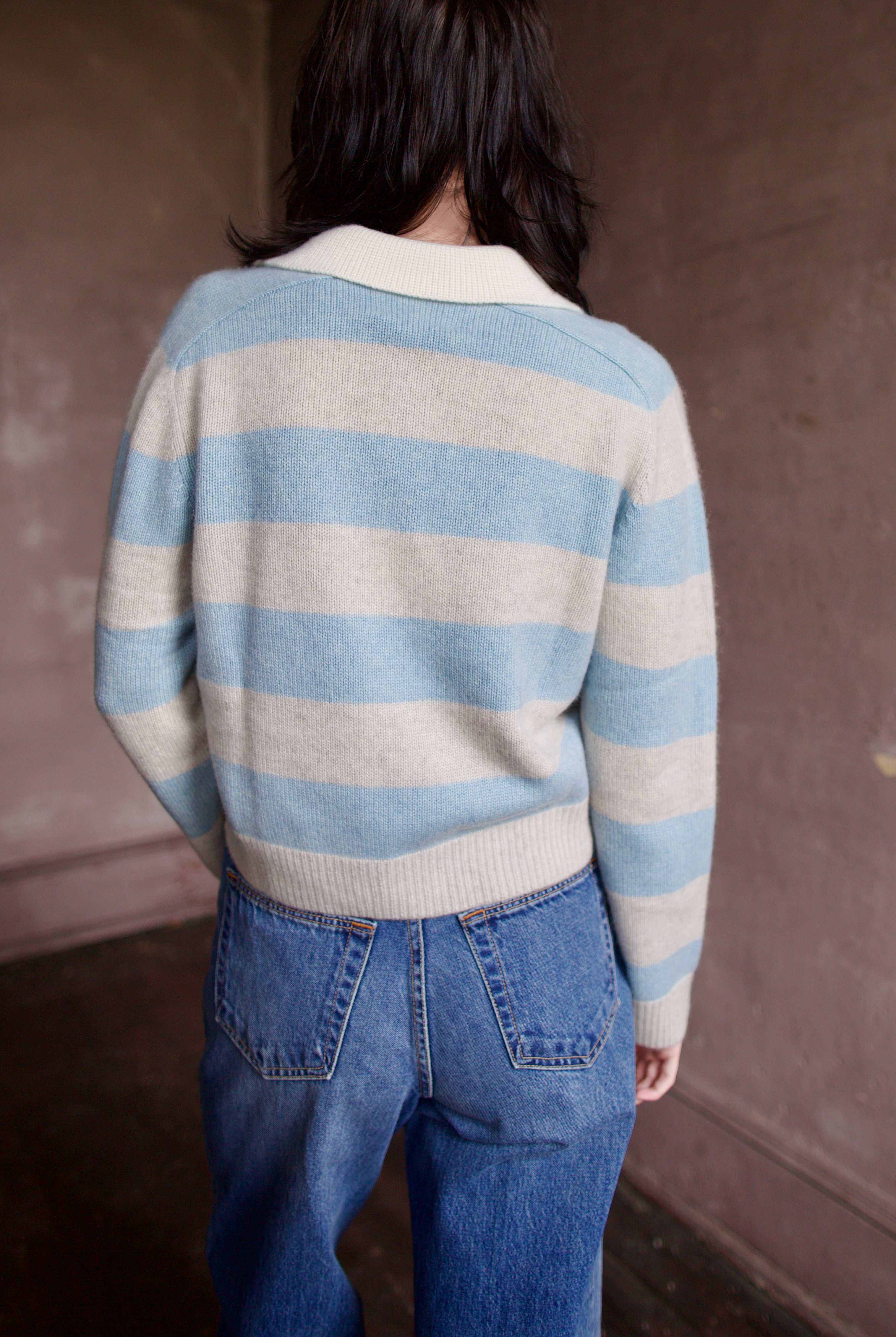 Woman wearing luxury brand Kujten Royce striped long sleeve cashmere polo sweater in light blue and grey