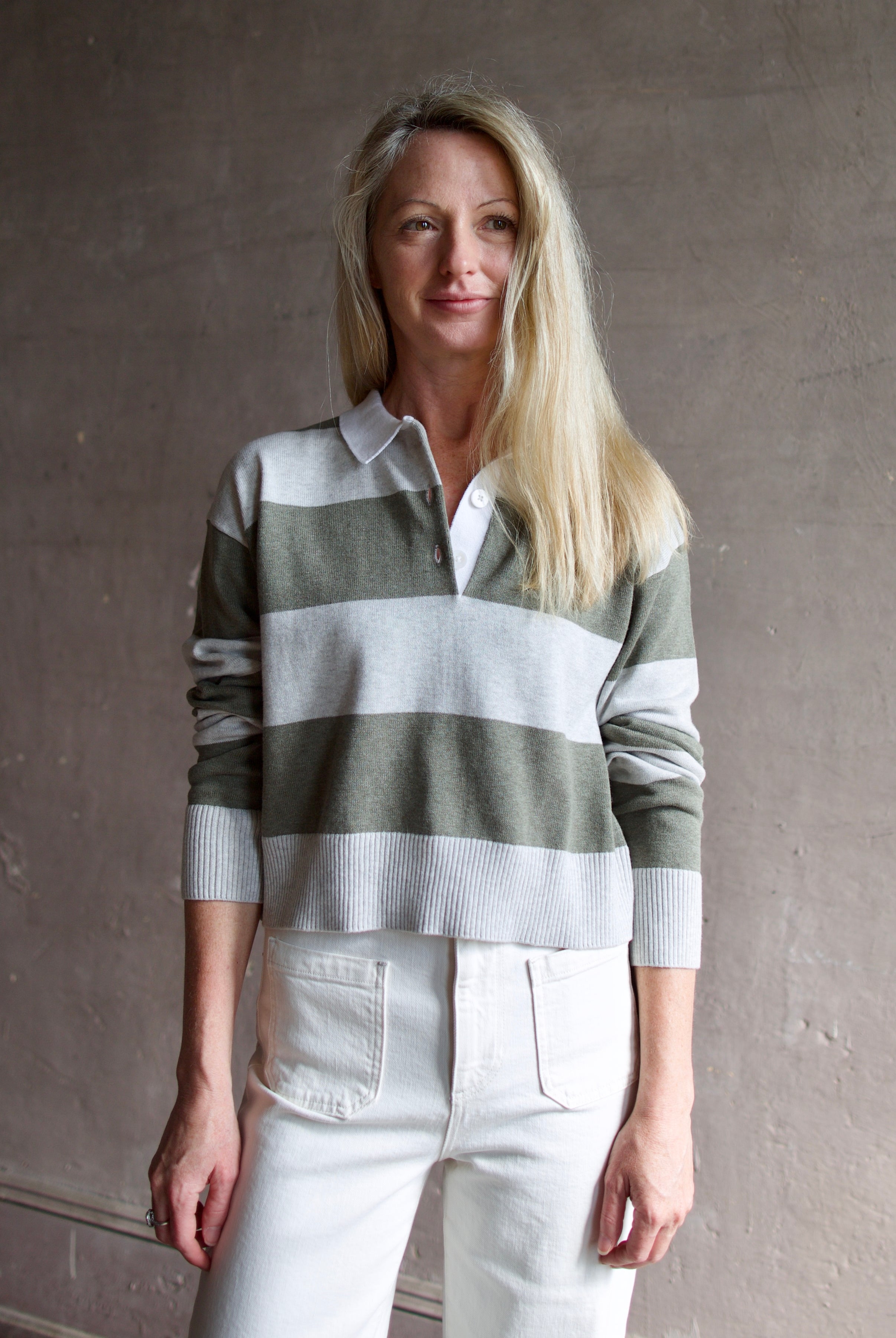 Model wearing Le Jean long sleeve polo in cotton and cashmere featuring a large green and gray stripe with a white collar.