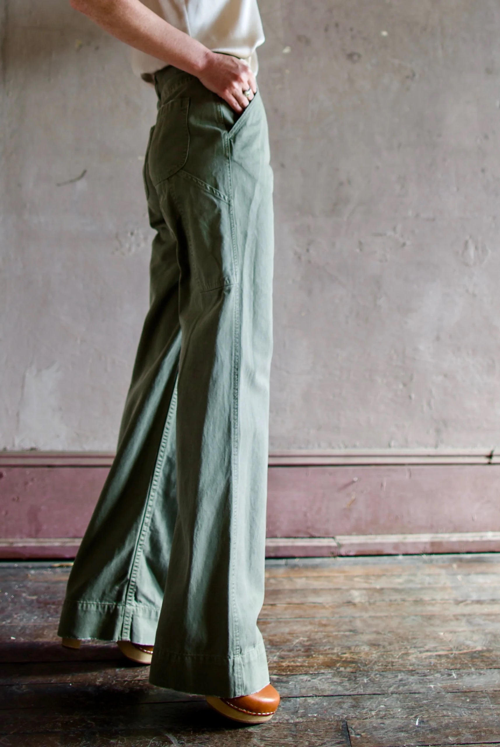 Image featuring a woman wearing the cotton Le Superbe werk pant with full length wide leg, high waist and side slant pockets in green.