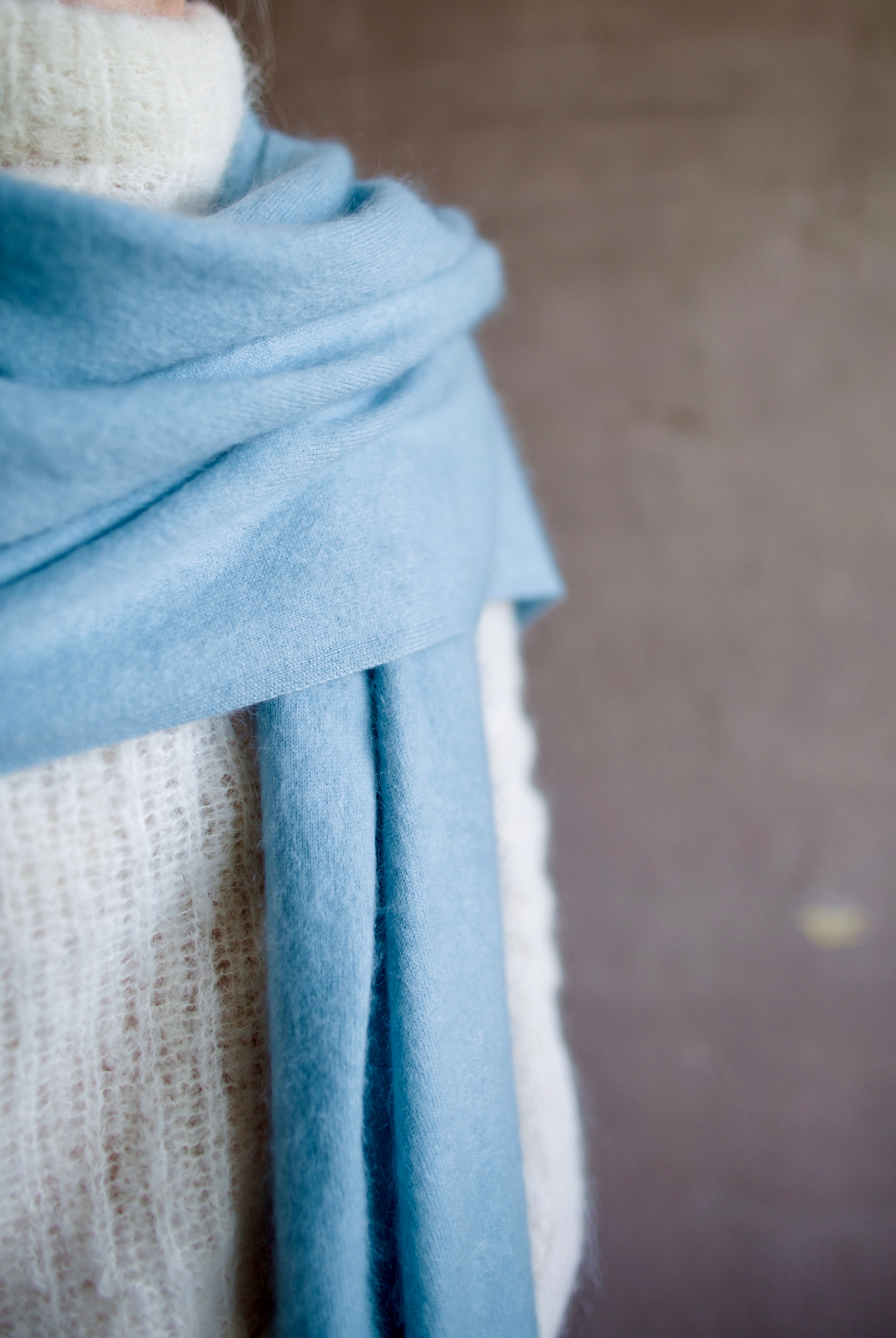Detail close up image featuring a woman wearing the brushed cashmere scarf by Lisa Yang in powder blue.