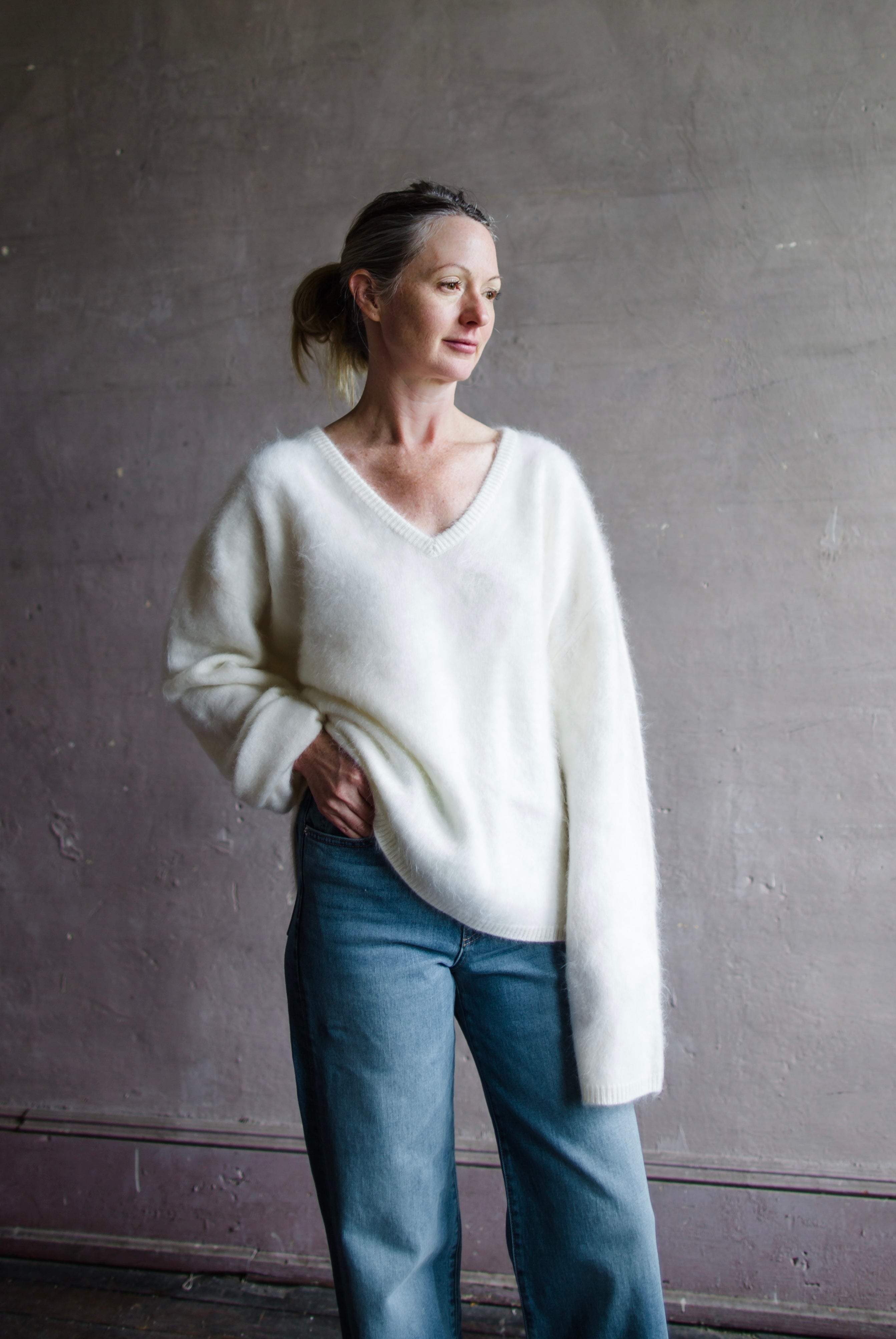 Image featuring a woman wearing the Margareta sweater by Lisa Yang with a deep v neckline, exaggerated sleeves in the softest ivory brushed cashmere.
