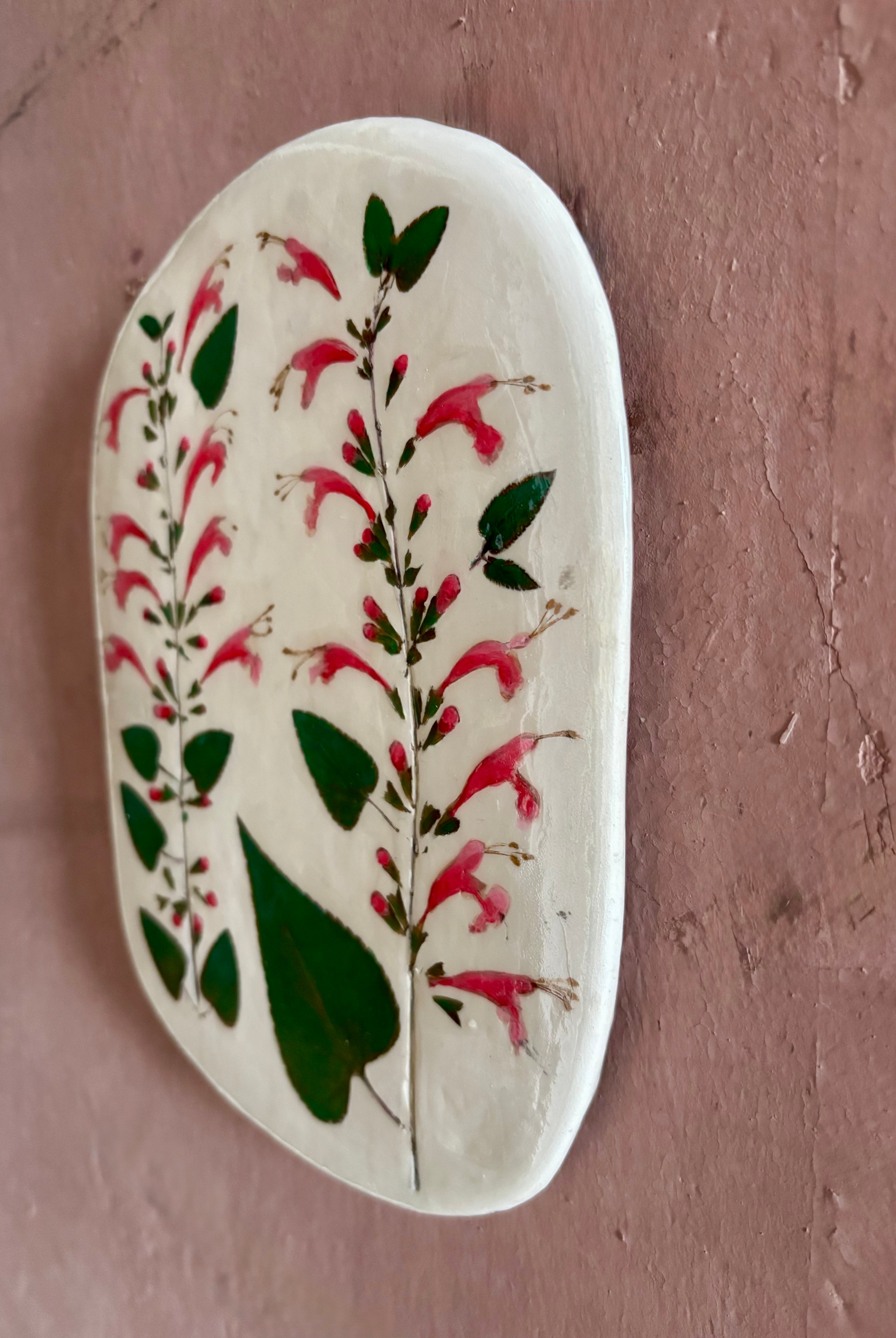 An oval ceramic tile with botanical black currant sage leaves pressed into cream-colored clay and air dried NC art