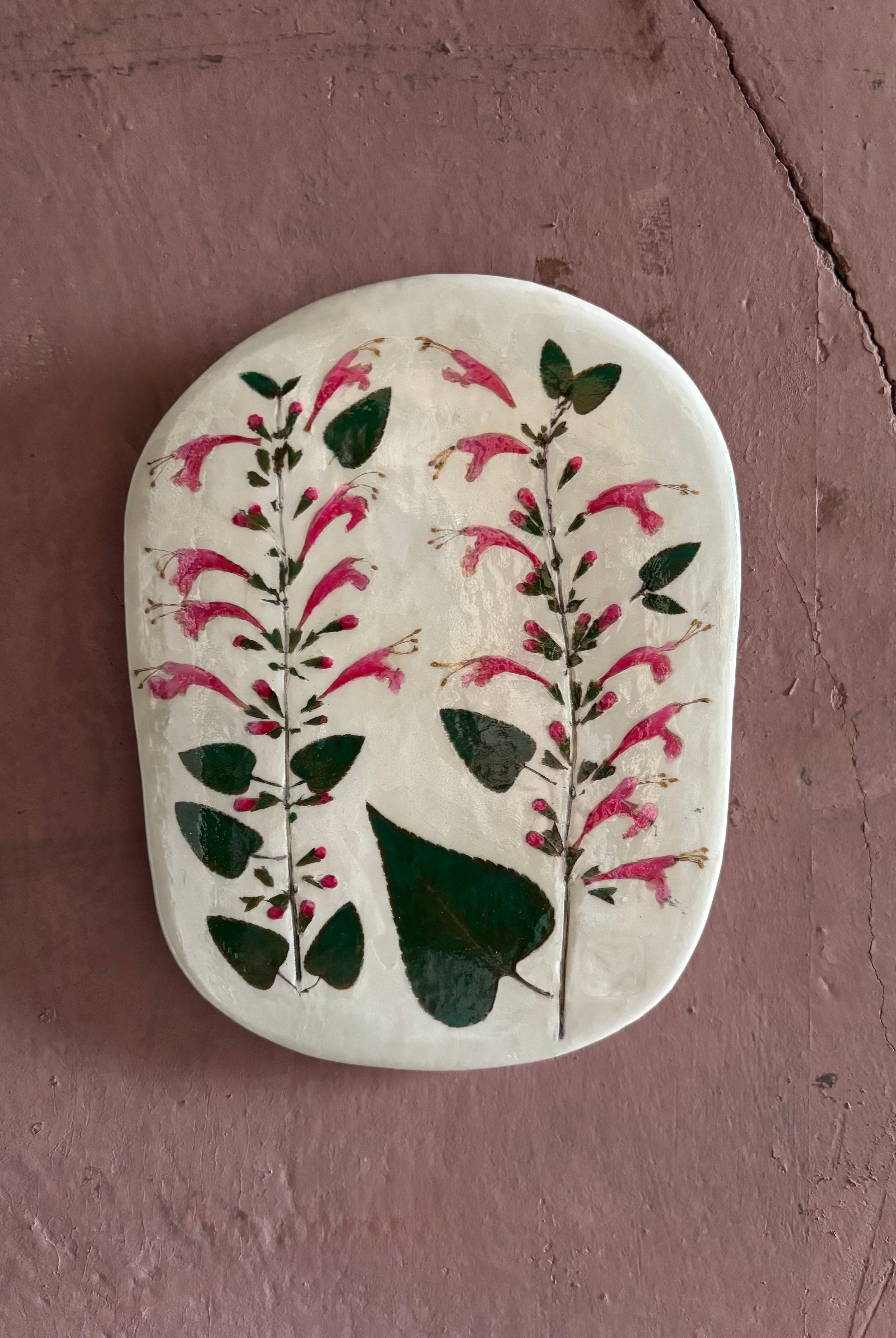 An oval ceramic tile with botanical black currant sage leaves pressed into cream-colored clay and air dried NC art