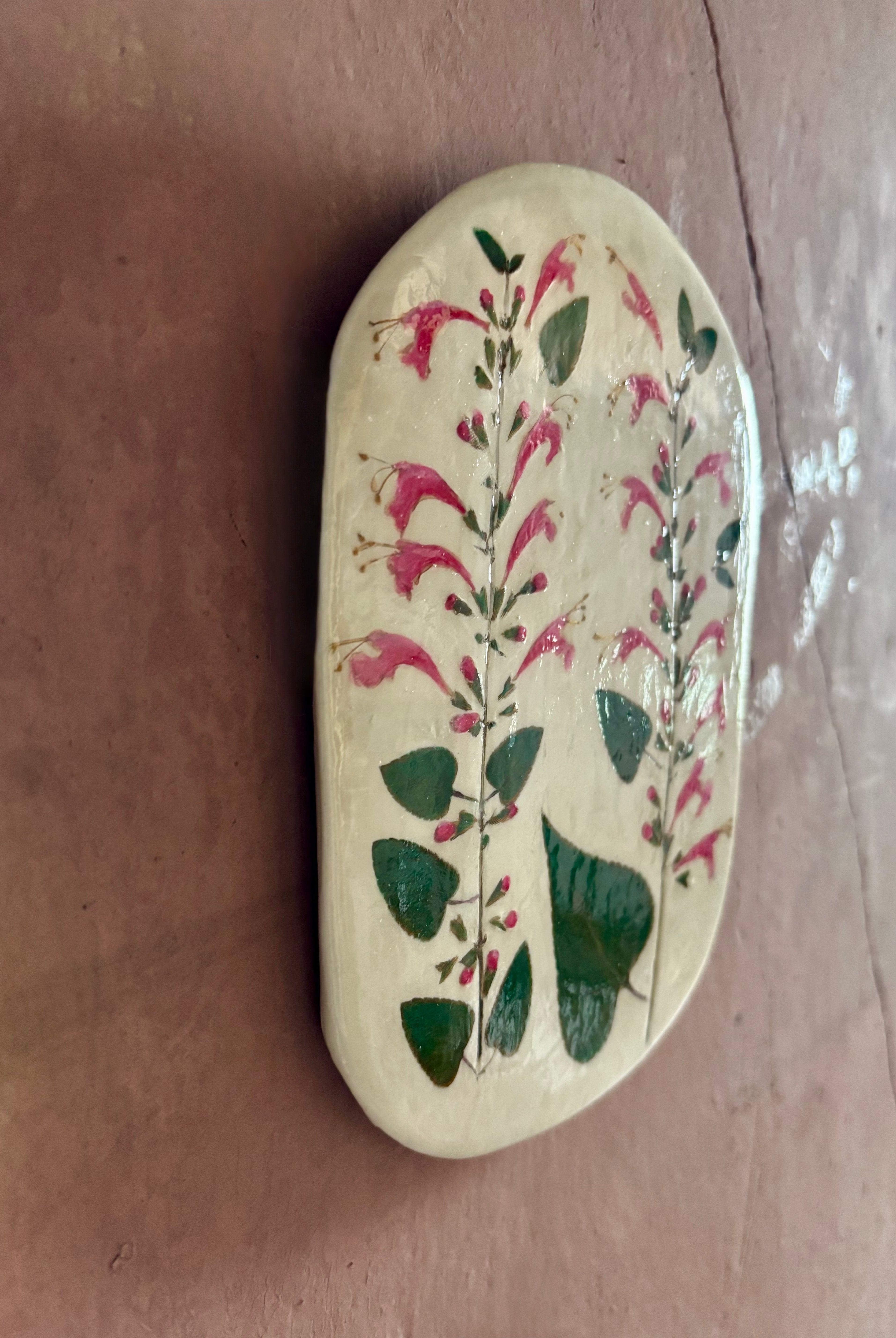 An oval ceramic tile with botanical black currant sage leaves pressed into cream-colored clay and air dried NC art