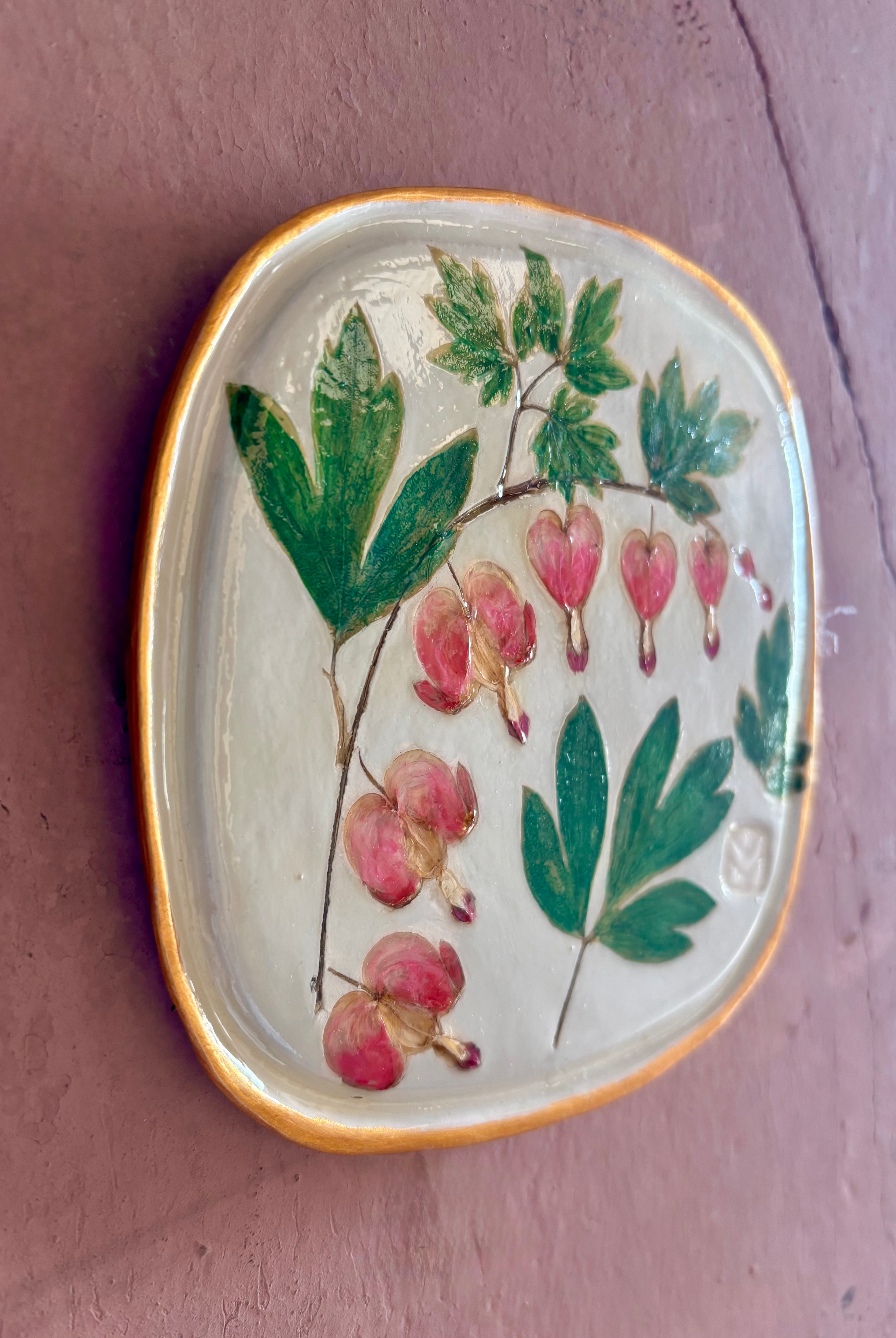 A square ceramic tile with botanical pressed bleeding heart flower stem and foliage on cream clay by NC artist