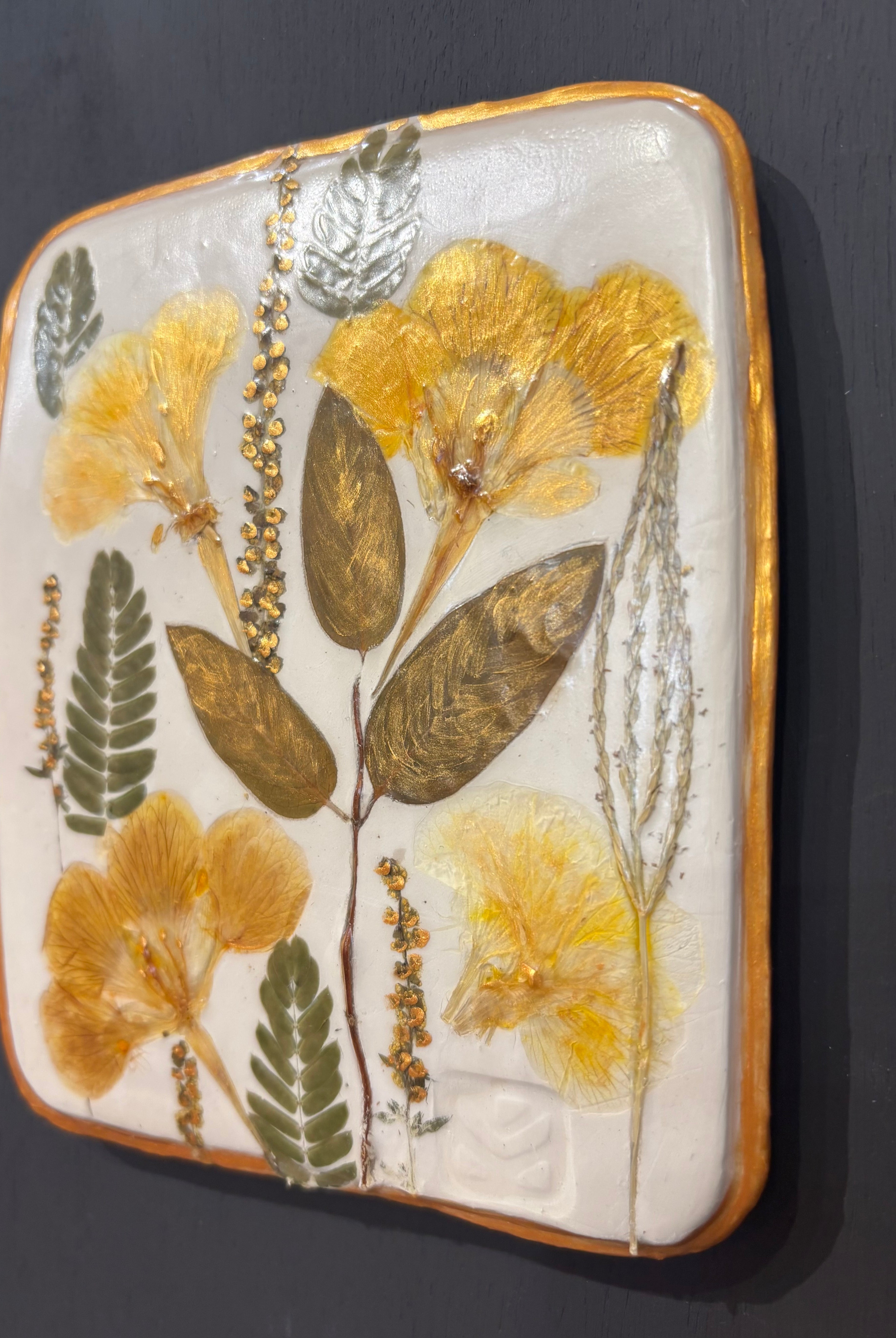 A square ceramic tile with botanical pressed wild evening yellow primrose and foliage on cream clay by NC artist