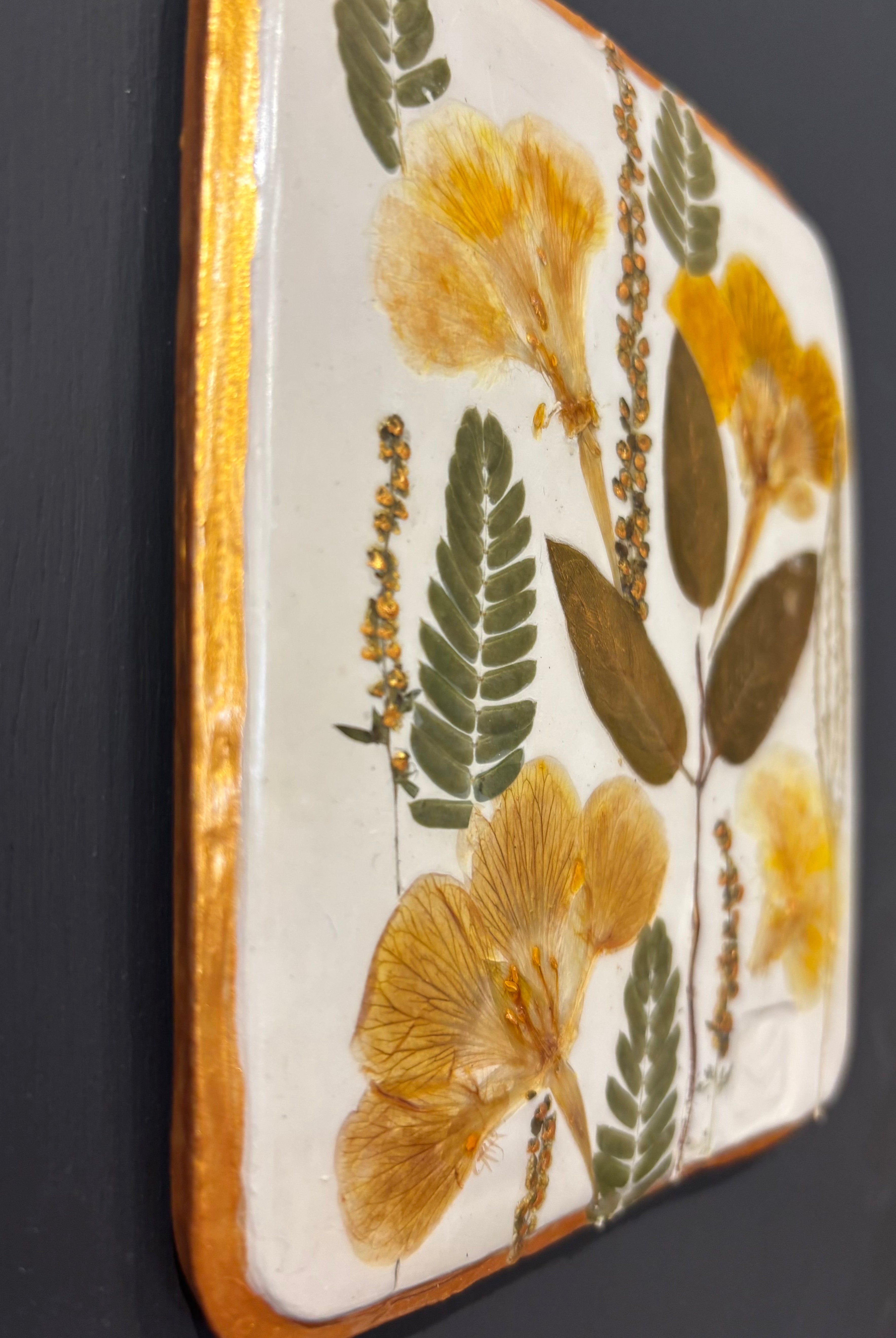 A square ceramic tile with botanical pressed wild evening yellow primrose and foliage on cream clay by NC artist