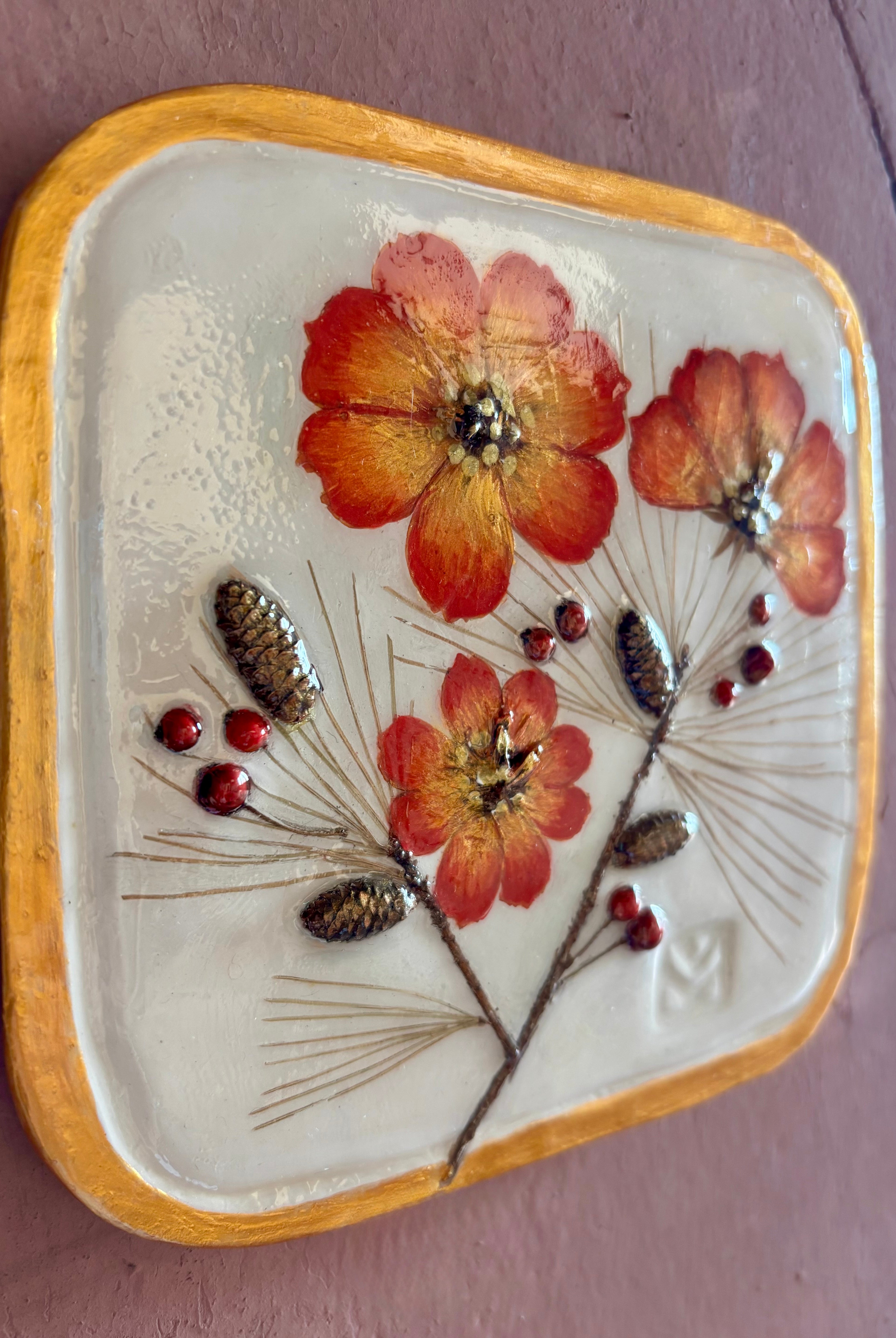 A square ceramic wall tile pressed botanical elements holly cosmos pine needles pinecones and red berries