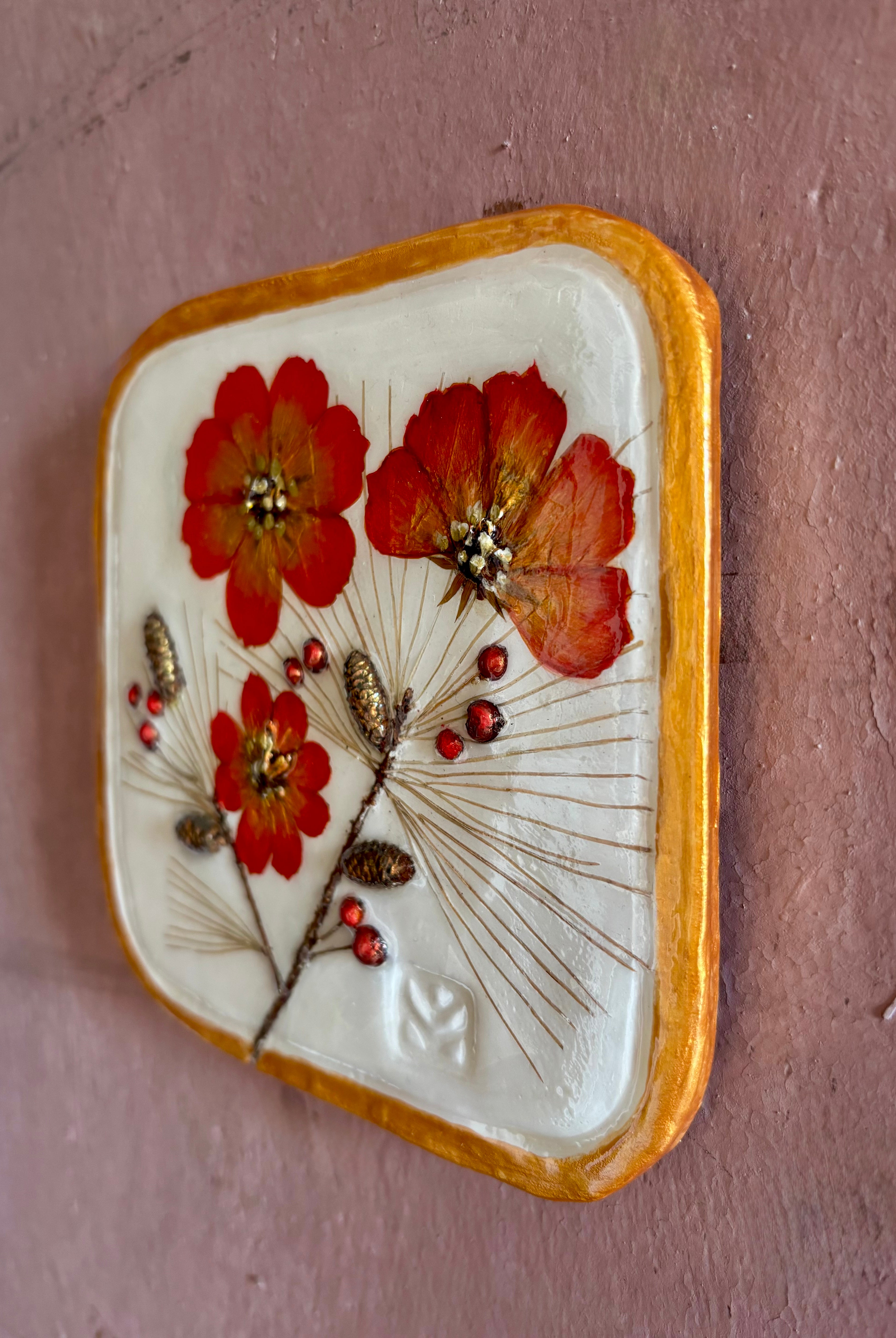 A square ceramic wall sculptural pressed botanical elements holly cosmos pine needles pinecones and red berries