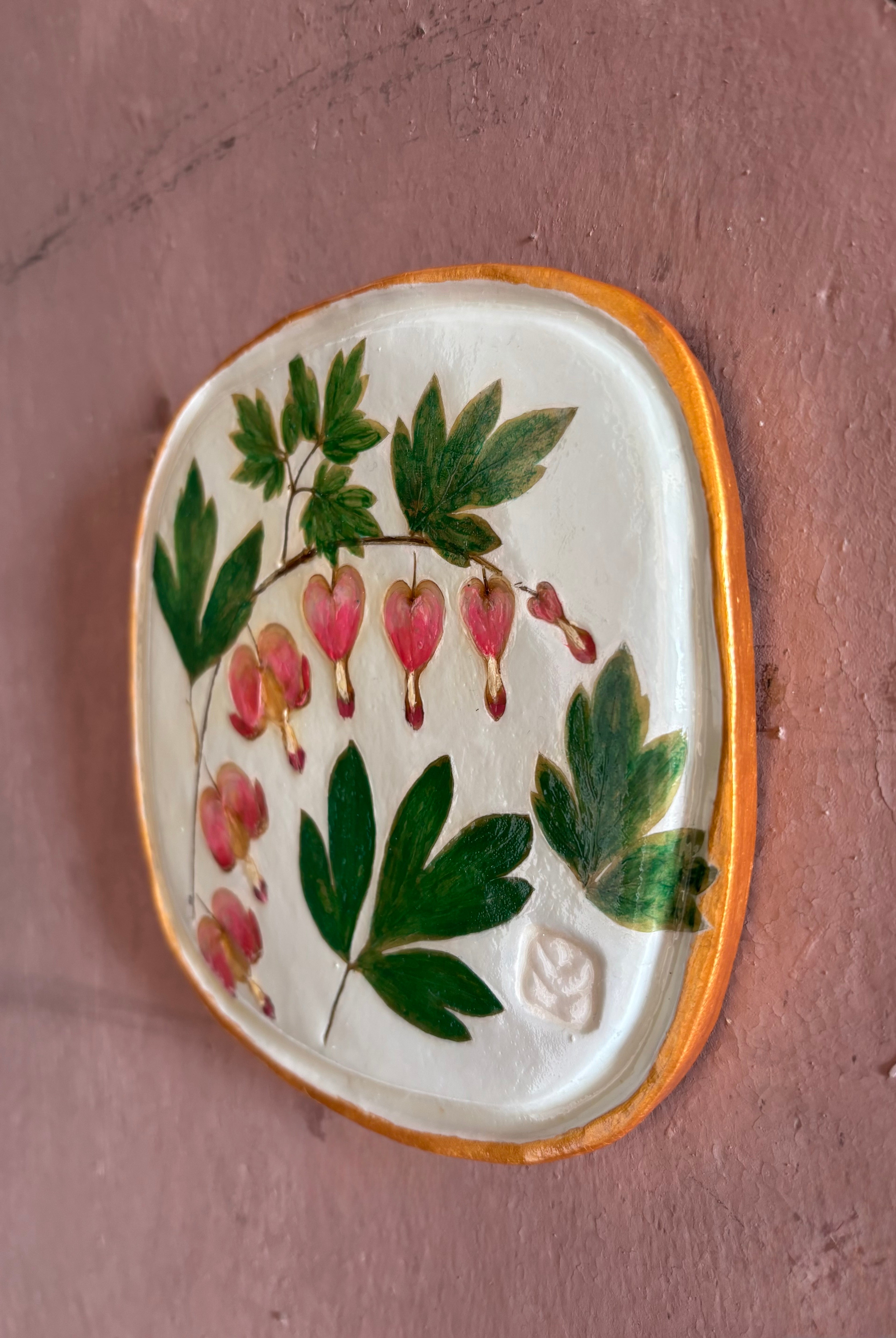 A square ceramic tile with botanical pressed bleeding heart flower stem and foliage on cream clay by NC artist