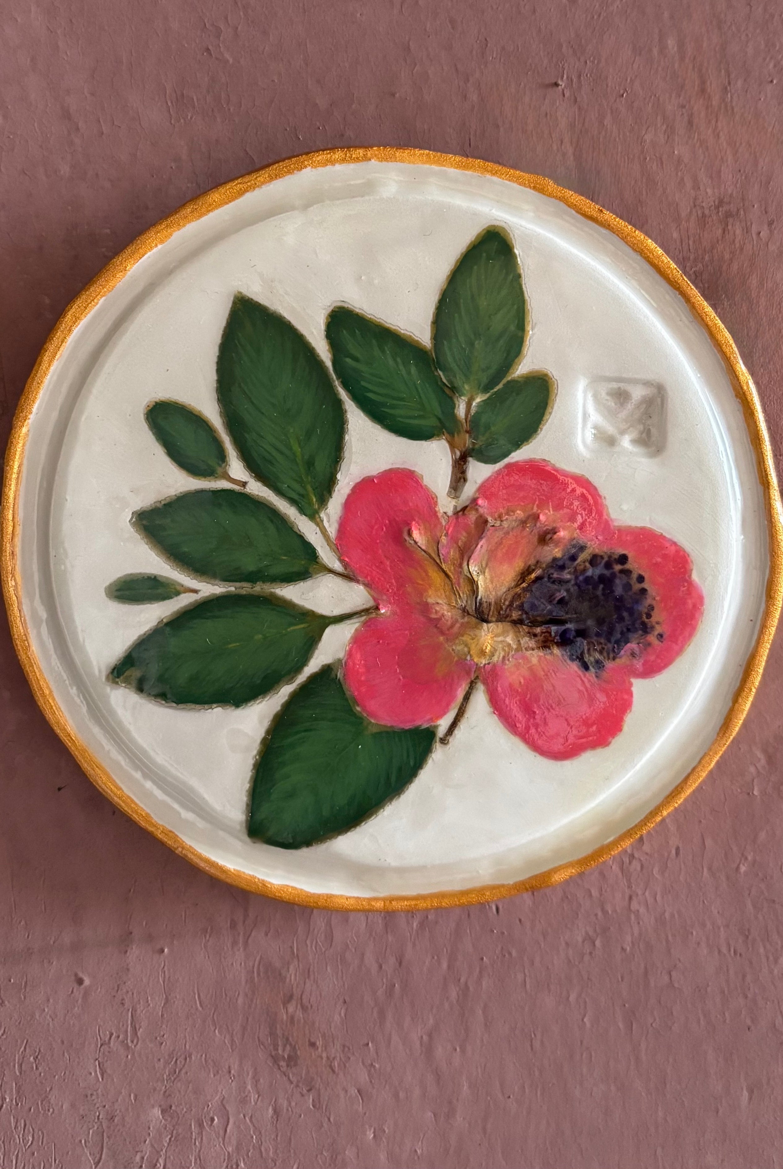 A round white ceramic tile with sappora rhododendron bloom botanical press green leaves and hand painted gold rim