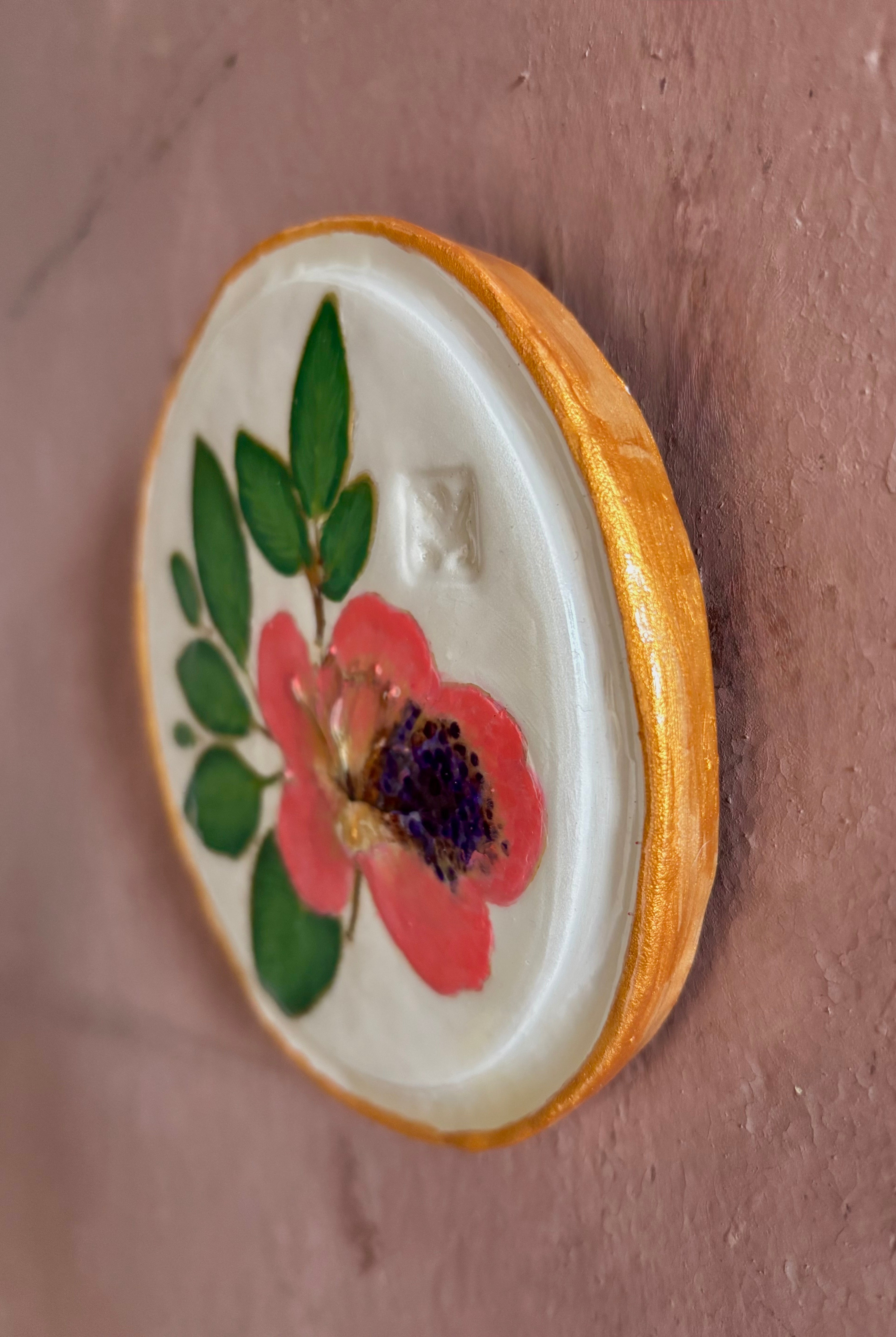 A round white ceramic tile with sappora rhododendron bloom botanical press green leaves and hand painted gold rim