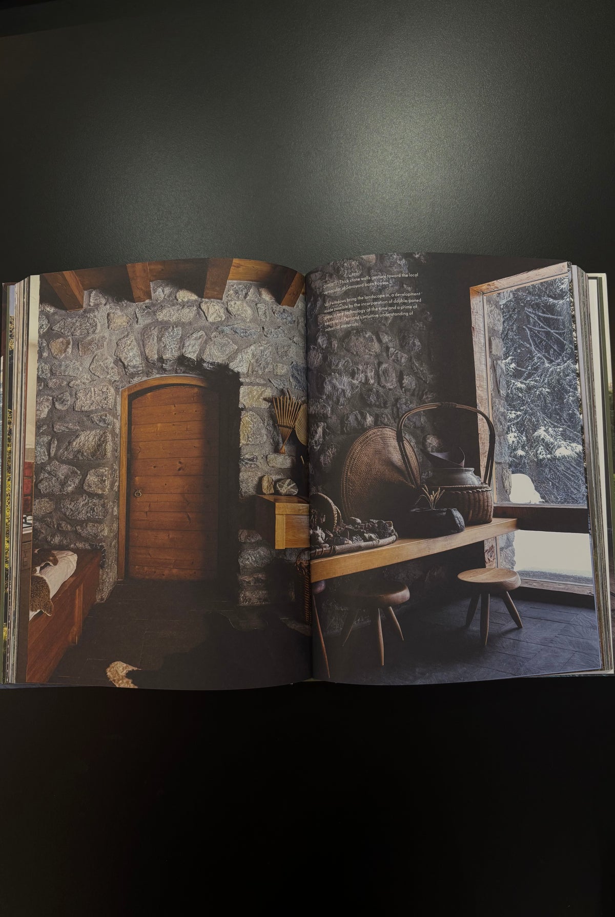 An open book or magazine spread showing a rustic interior scene with stone walls wooden door table window